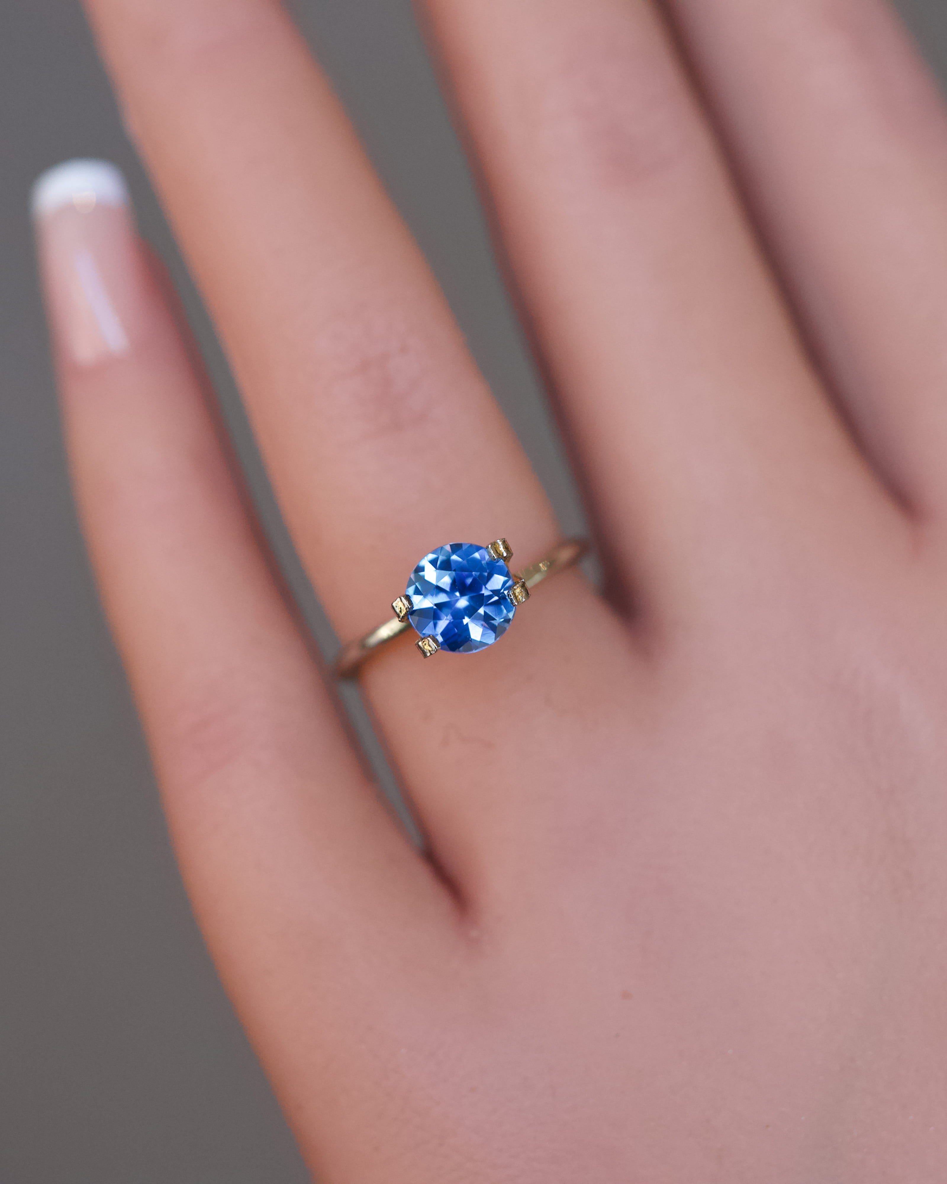 Close-up of a heated blue Ceylon round sapphire in a temporary ring setting.