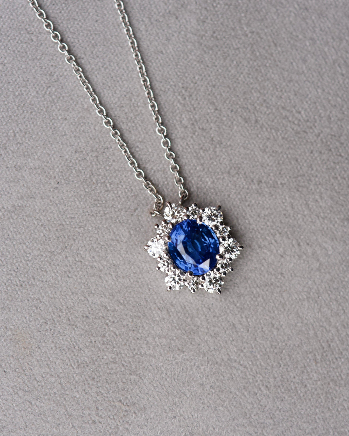 Blue sapphire pendant with diamond halo, flat lay