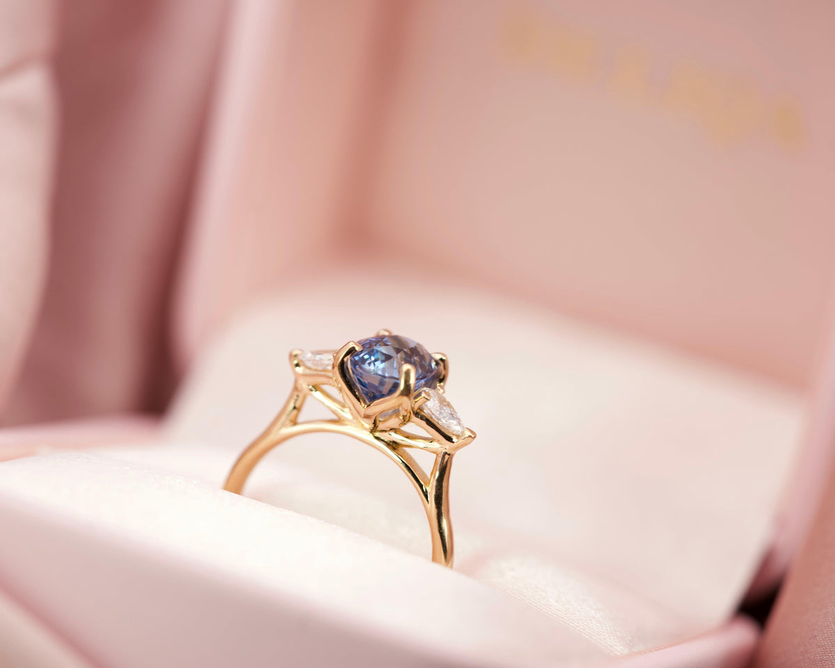 Luxury blue sapphire trilogy engagement ring presented in a signature pink velvet jewellery box