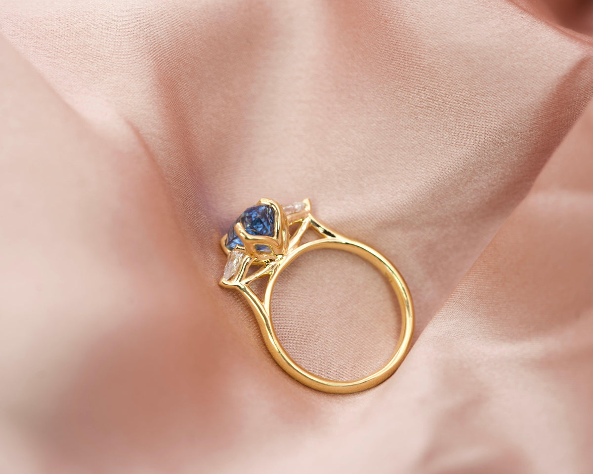 Side profile of an 18k yellow gold trilogy ring showing the raised setting designed to fit a wedding band flush
