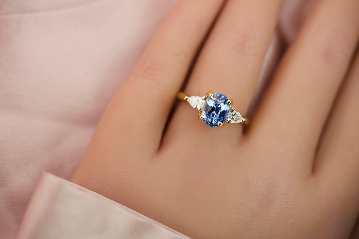 Oval blue sapphire and pear diamond ring worn on a hand showing its elegant scale and proportions
