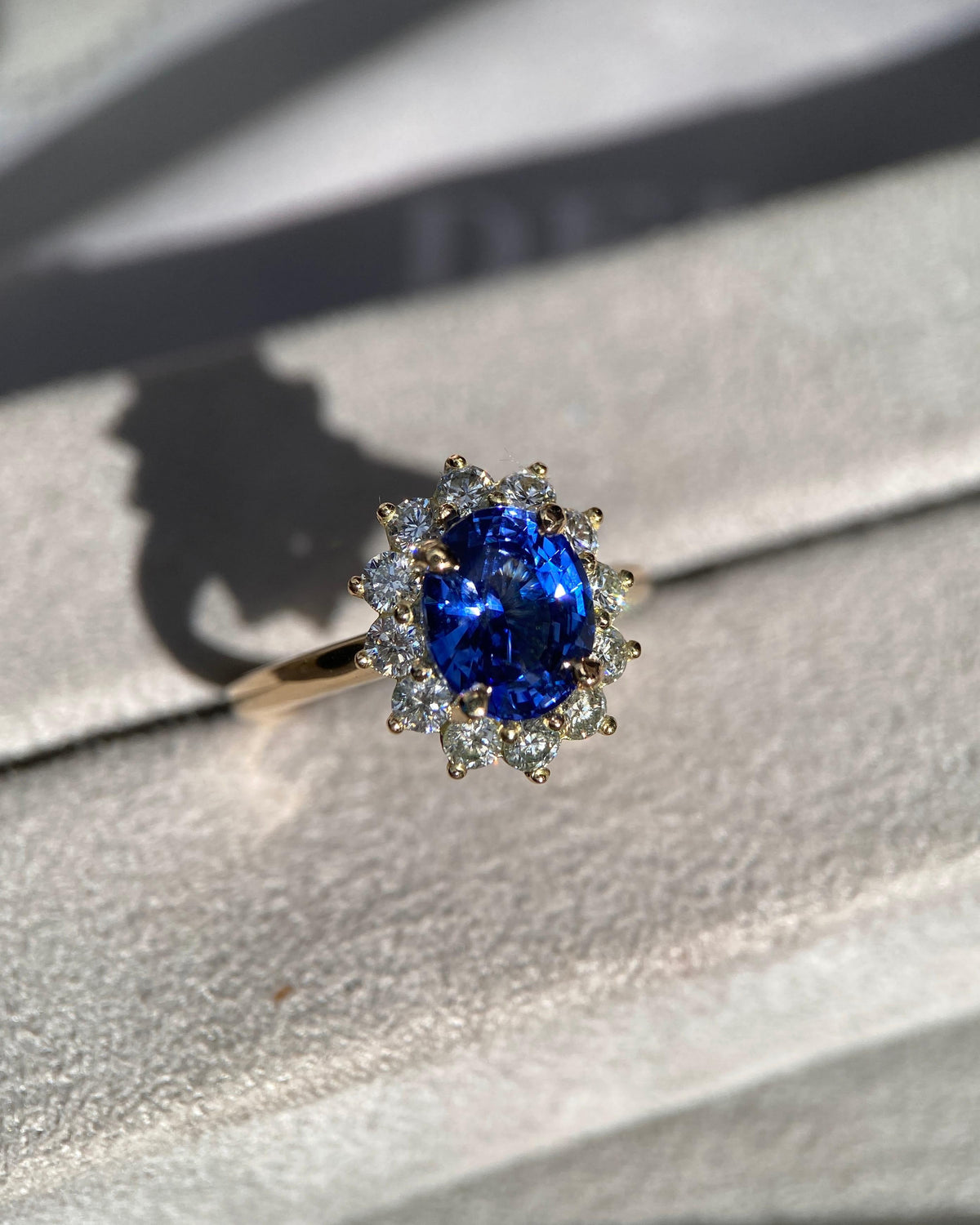 Vivid blue sapphire engagement ring catching direct sunlight to show internal fire and diamond sparkle
