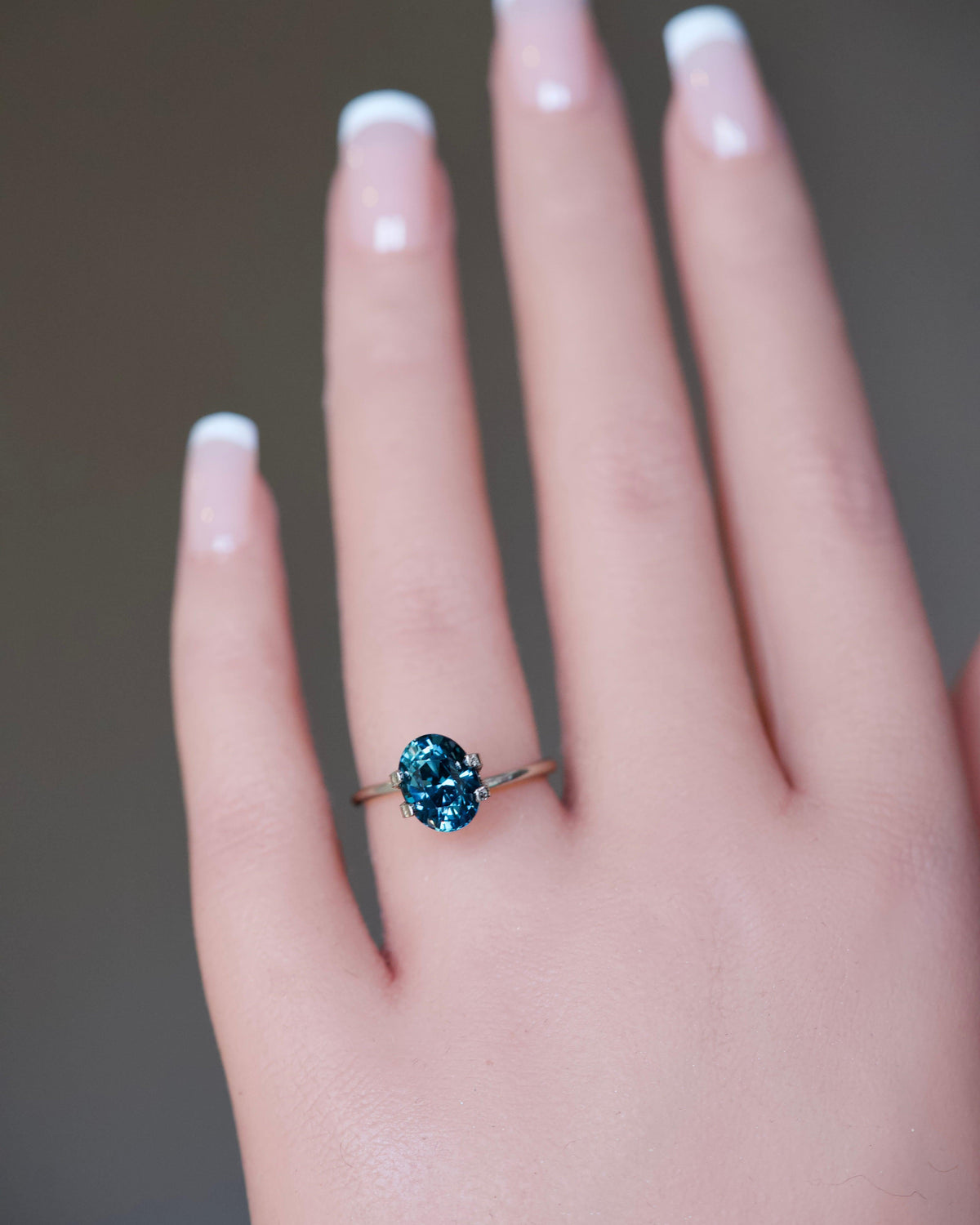 A massive 3.13 carat natural unheated bluish-green oval sapphire presented on a model's ring finger.