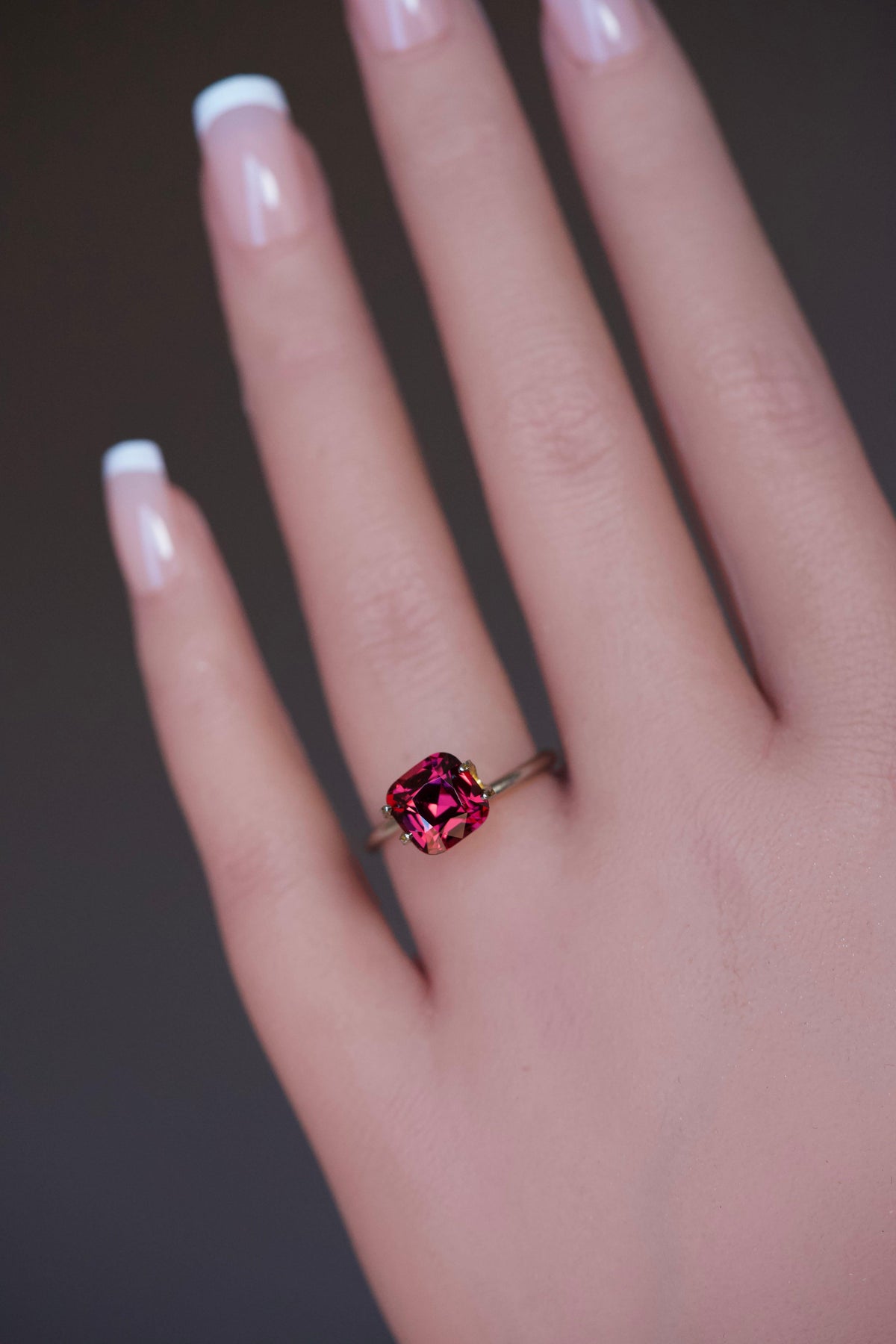 Magenta square cushion garnet stone presented on a hand.