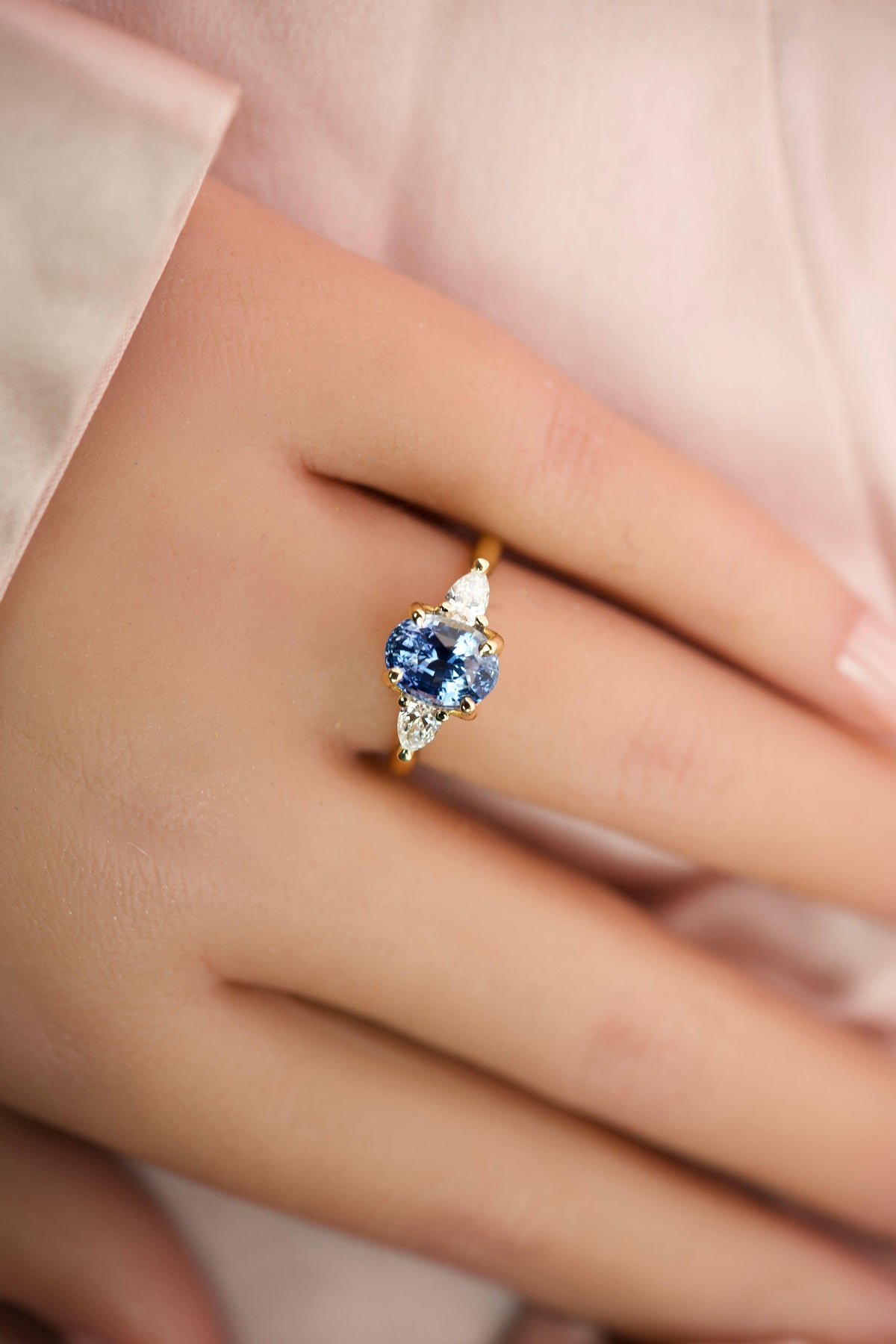 Full hand view of a handcrafted 18k yellow gold blue sapphire and diamond trilogy ring