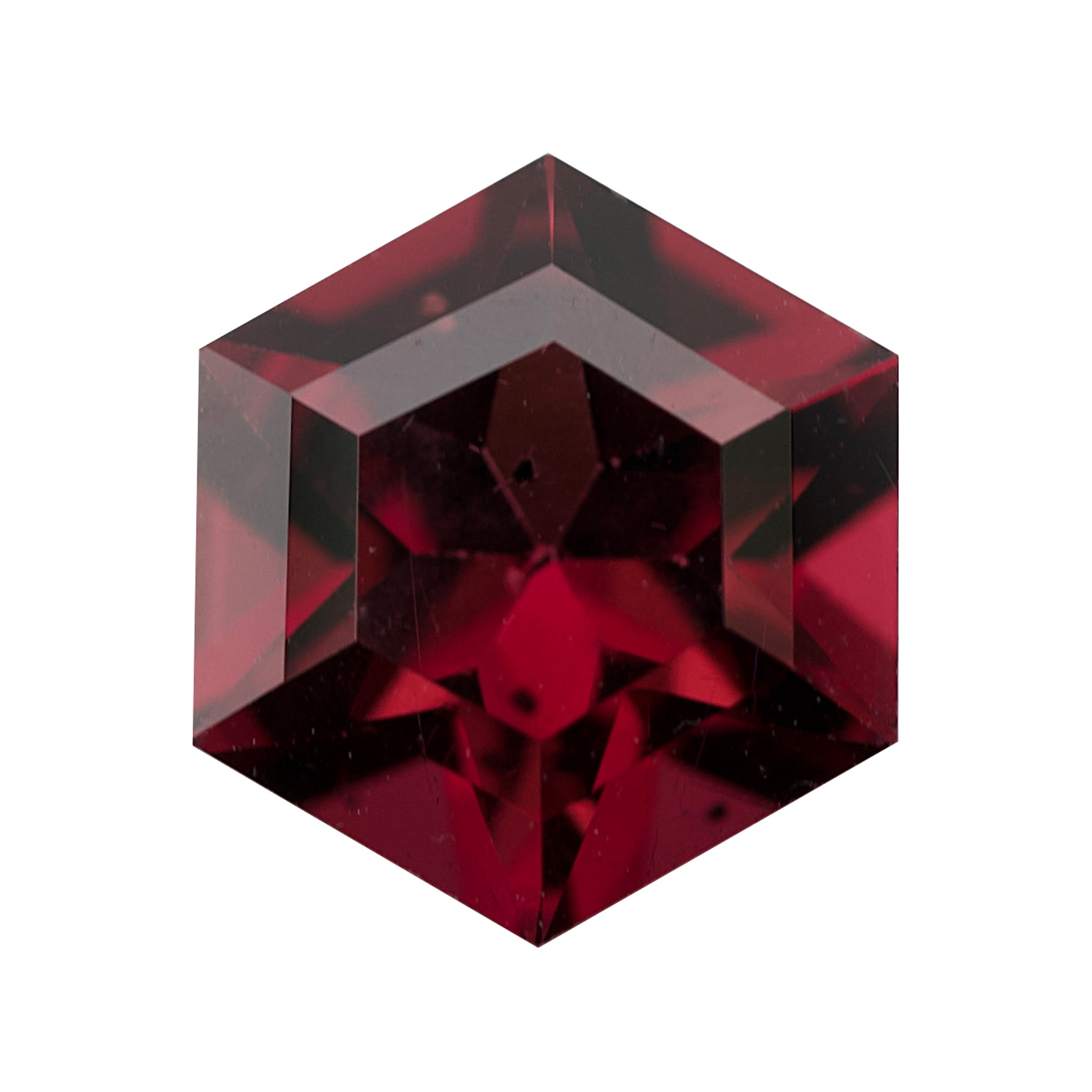 Deep red six-sided geometric fancy-cut garnet on a white background.