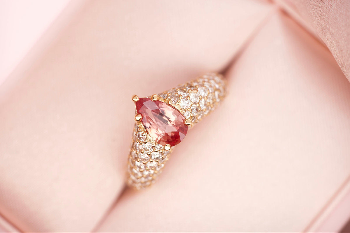 Padparadscha sapphire ring worn on hand, close-up