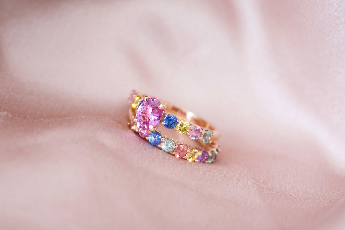 Pink sapphire engagement ring stacked with rainbow band