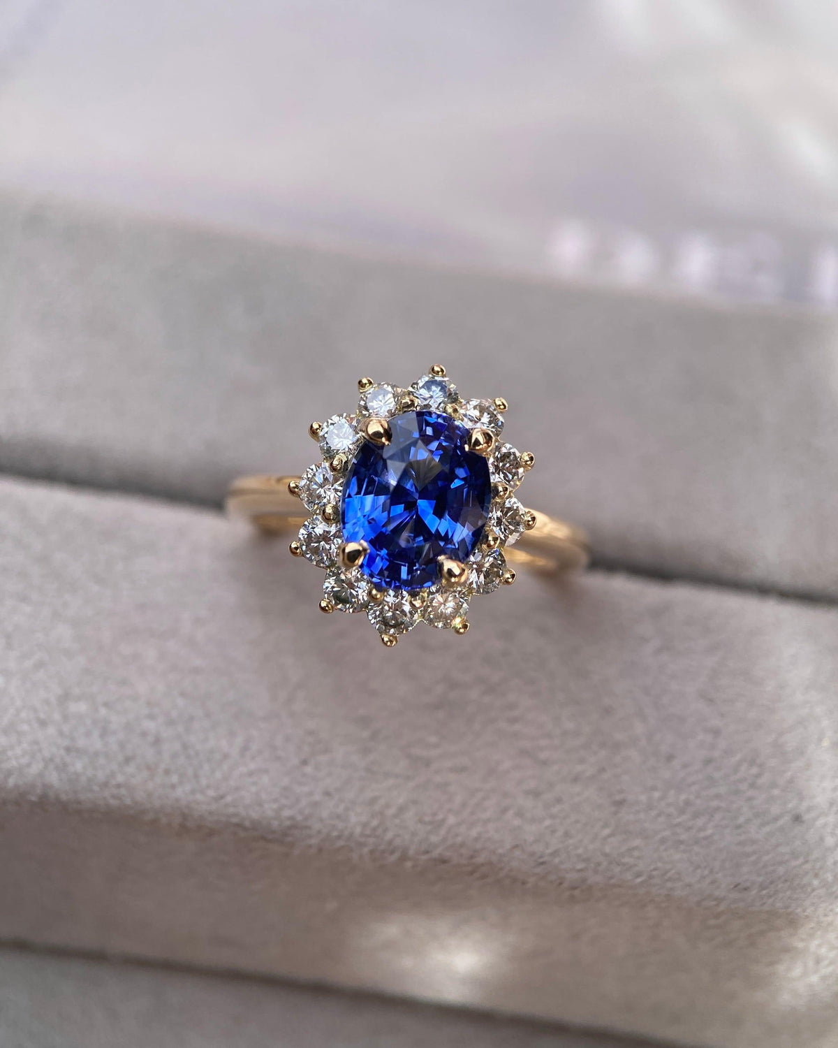 Classic royal style blue sapphire ring with a prominent diamond scalloped halo setting