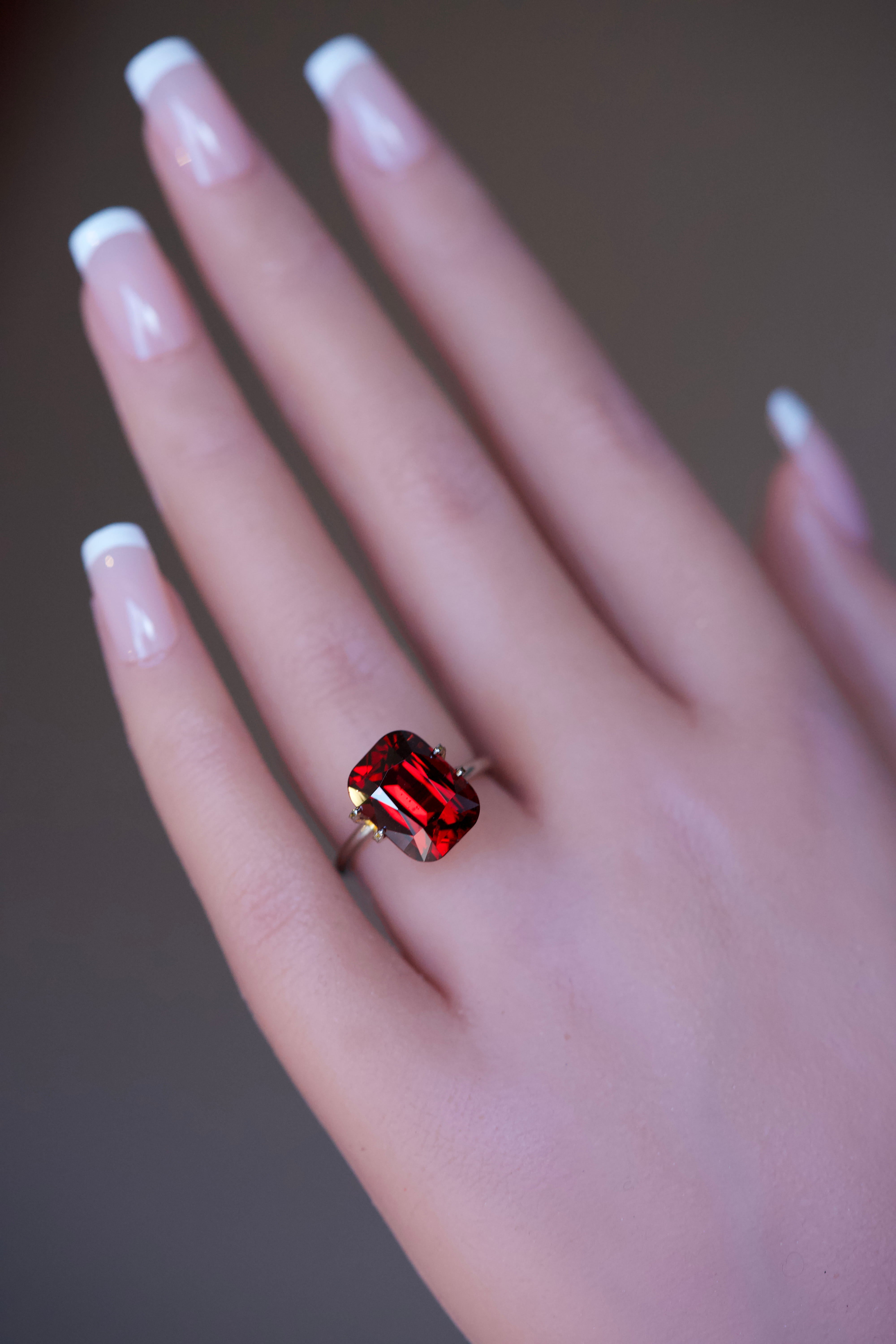 Orangish red rhodolite garnet cushion ring mockup on a hand.