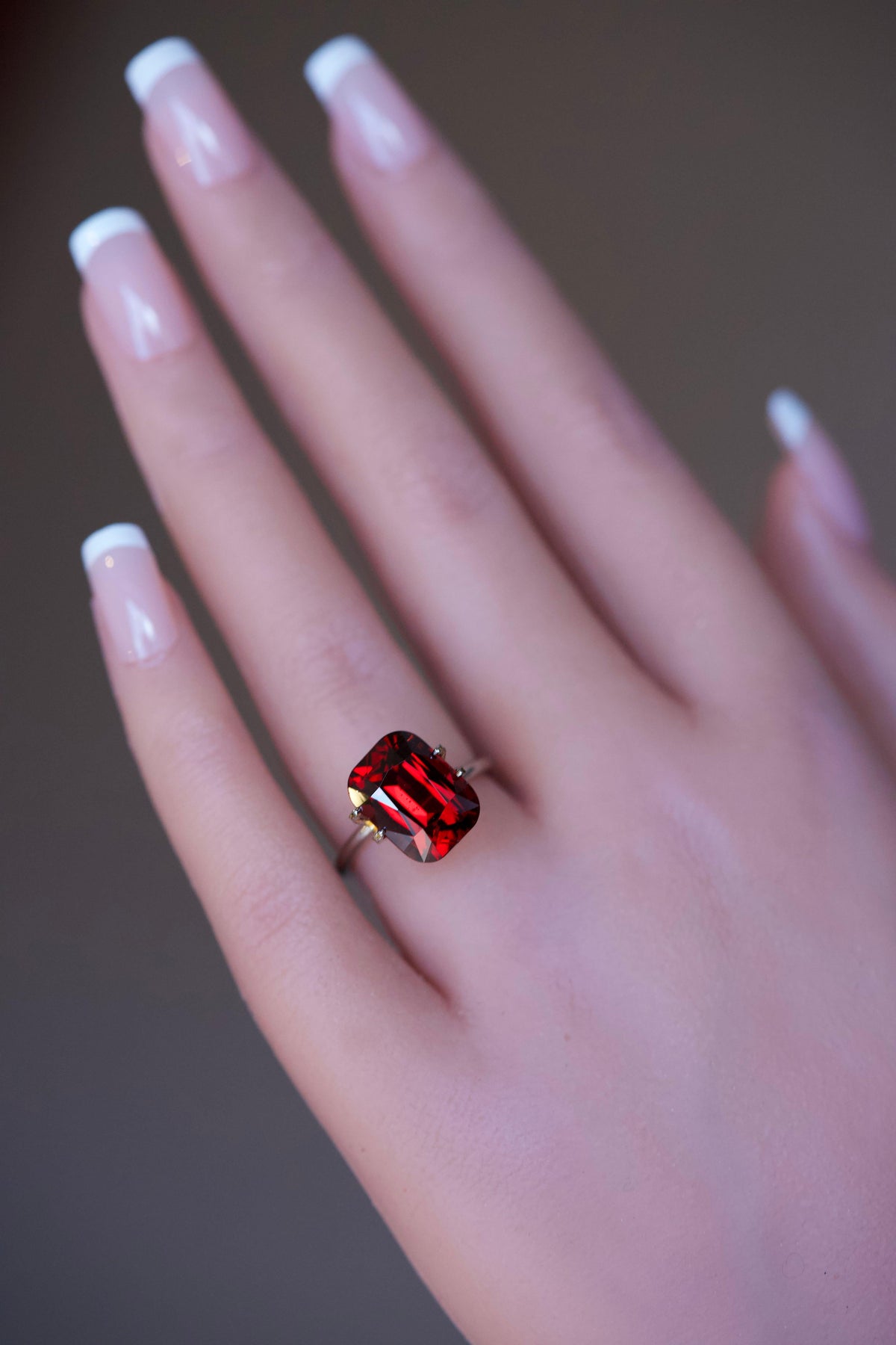 Orangish red rhodolite garnet cushion ring mockup on a hand.