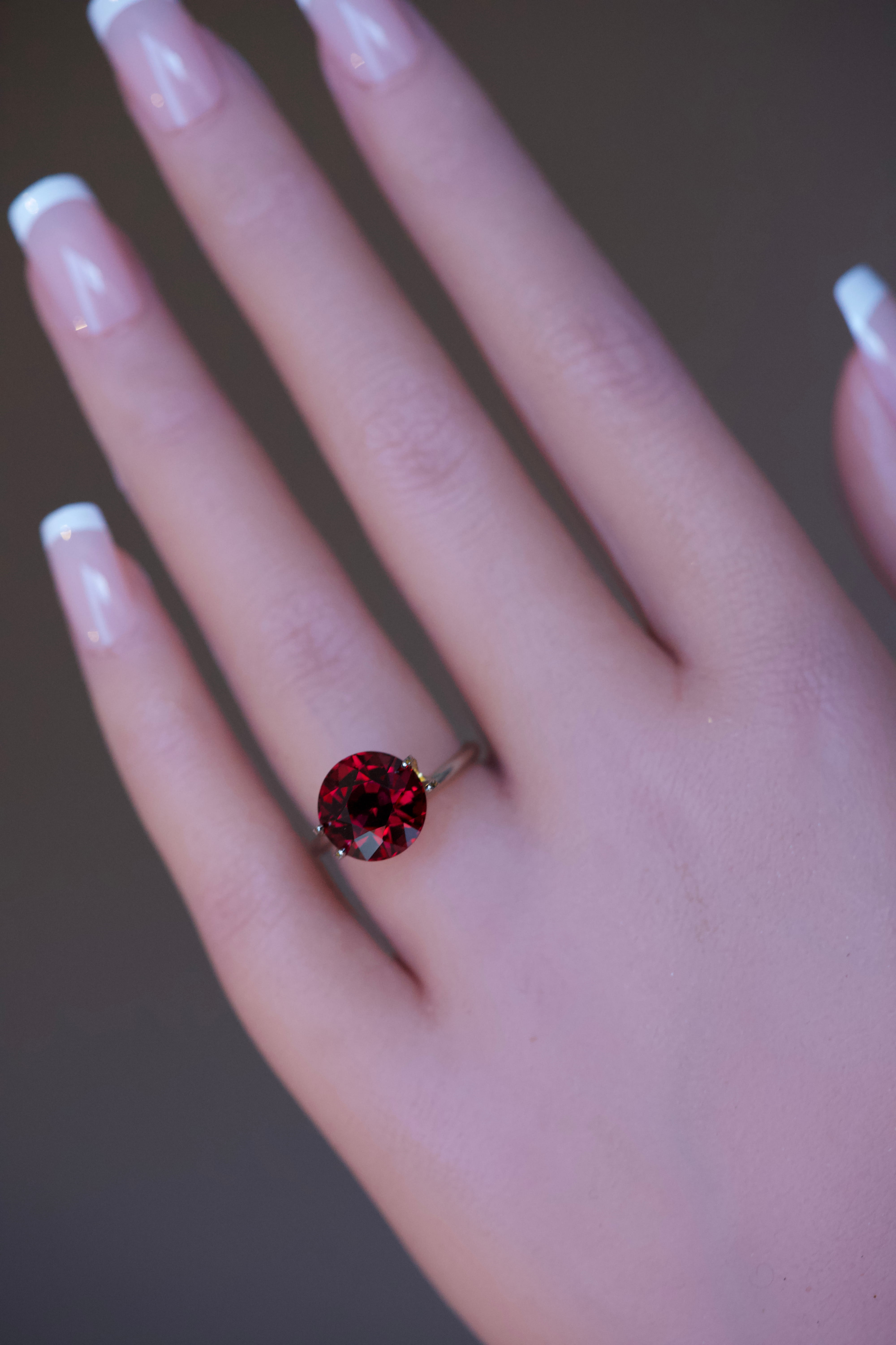 Circular red garnet stone tried on a model's finger.