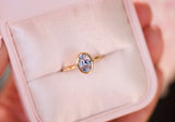 Oval blue sapphire bezel ring in yellow gold, in pink box