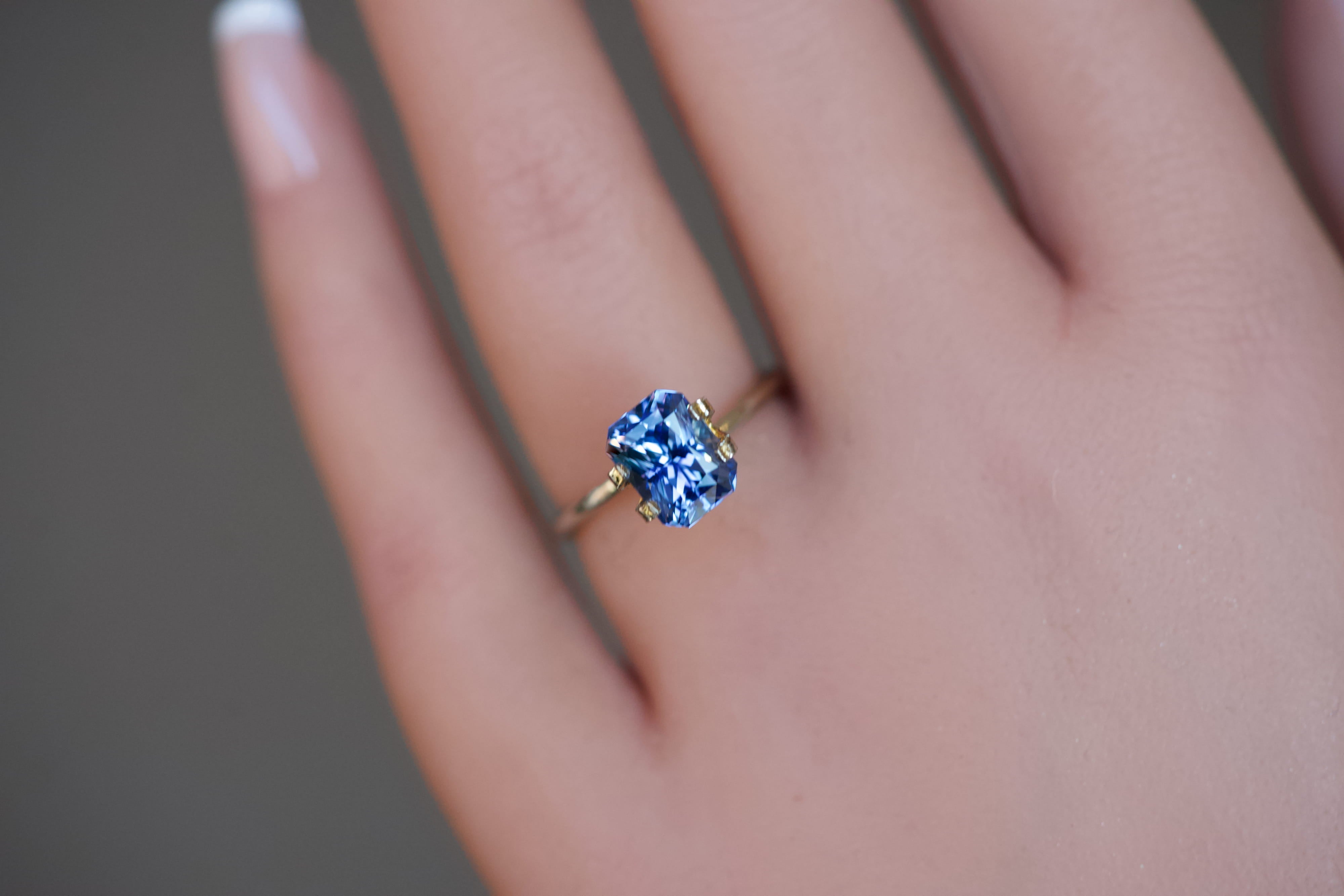 An impressive, unheated royal blue octagonal Burmese sapphire presented in a gold mock-up ring on a model's hand.