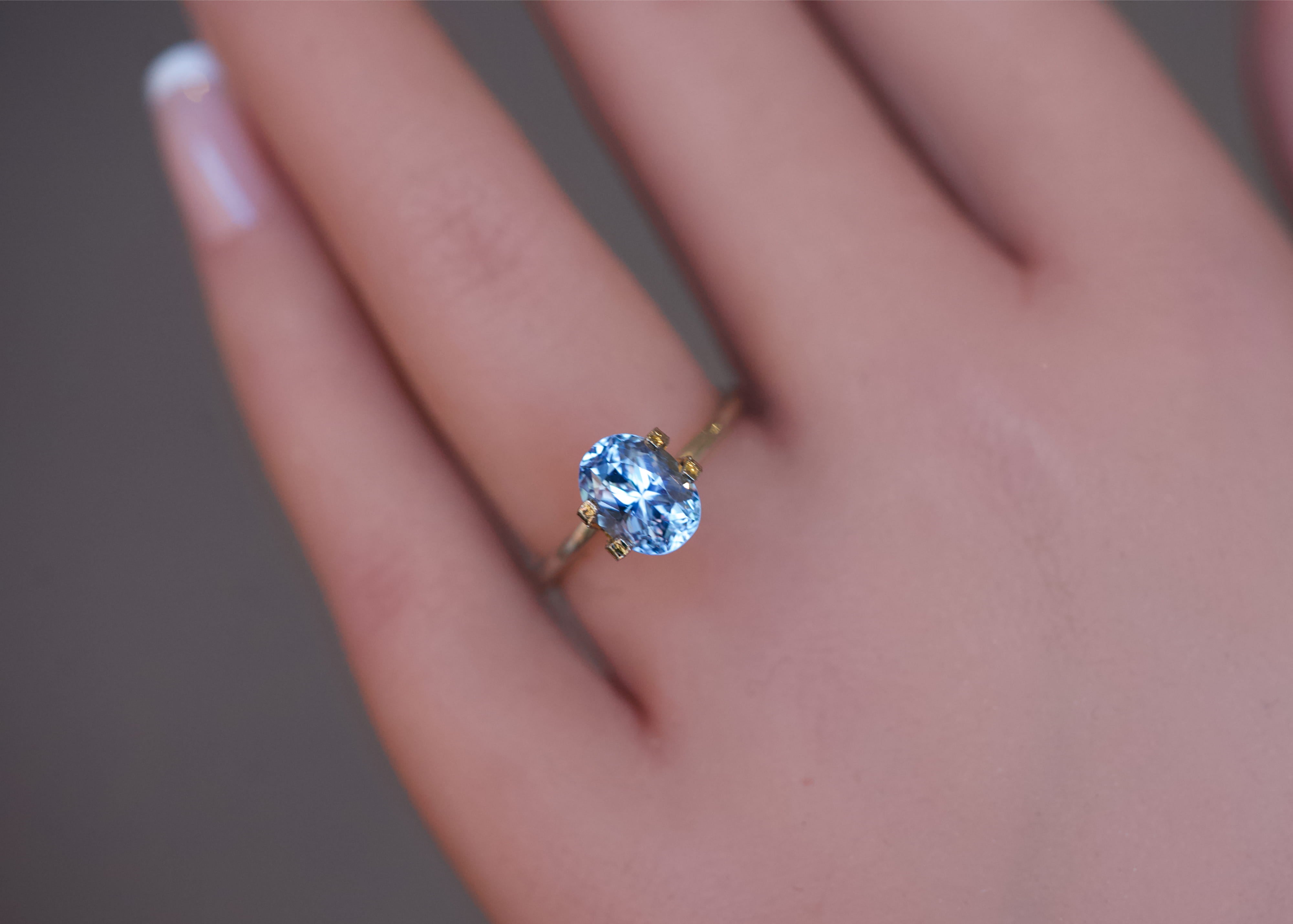An unheated blue Ceylon oval sapphire showcased in a temporary gold ring setting.
