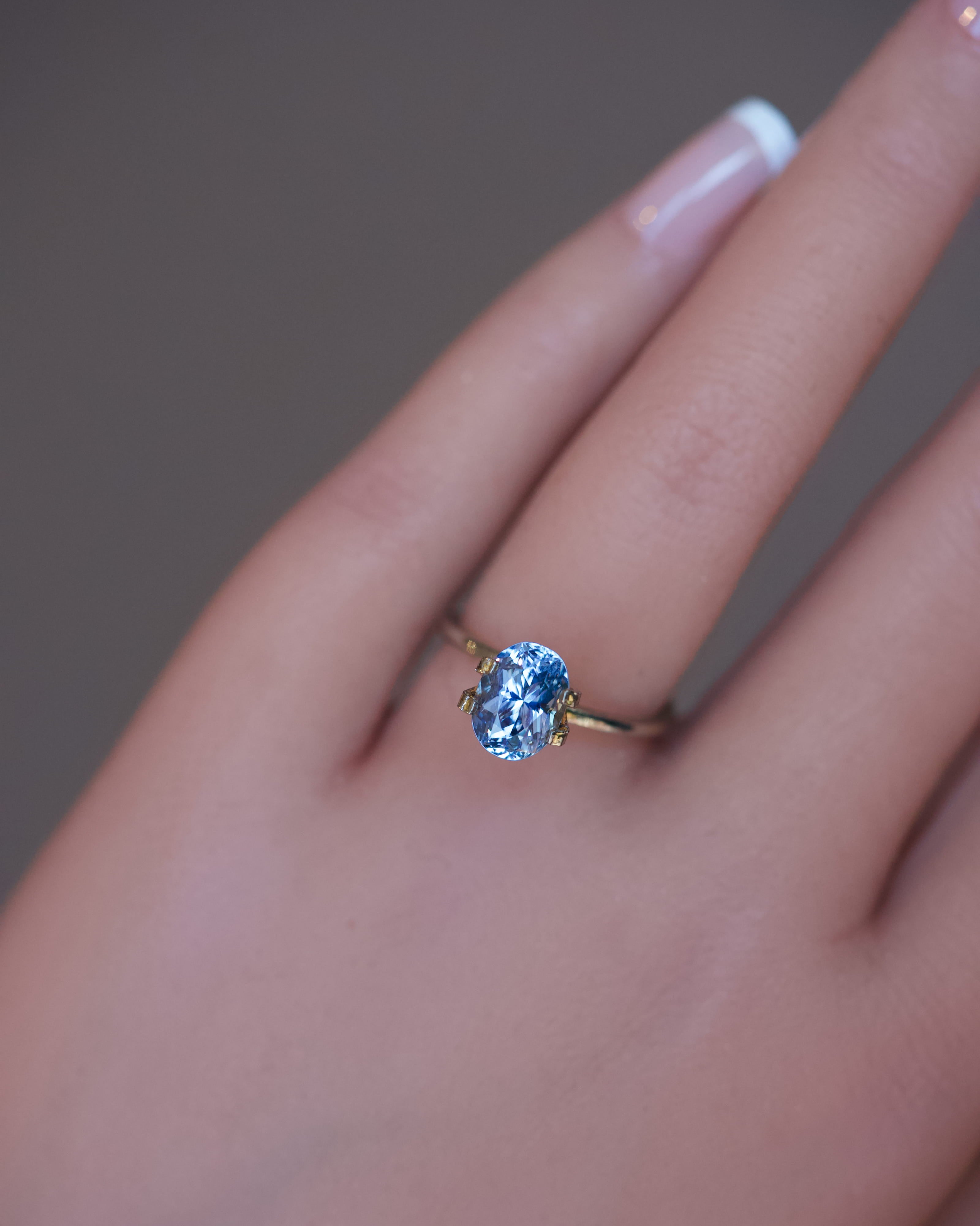 Detailed view of a blue unheated Ceylon oval sapphire modeled on a hand.