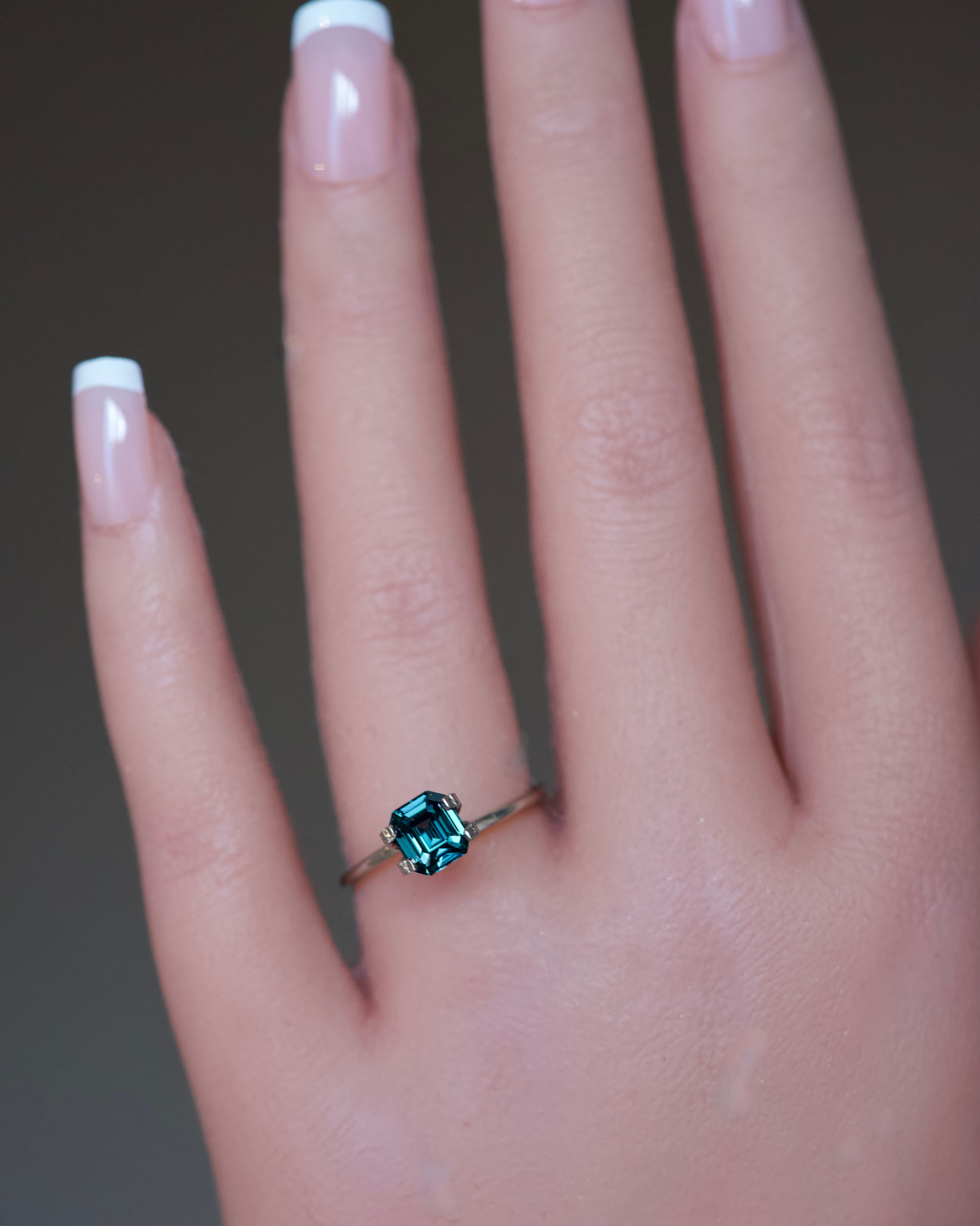 Unheated 1.69 carat emerald-cut green sapphire showcased in a gold ring mockup on a model's hand.