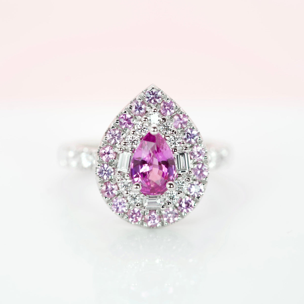 Frontal macro view of a 1.27 ct pear pink sapphire with baguette diamond halo and pink sapphire border