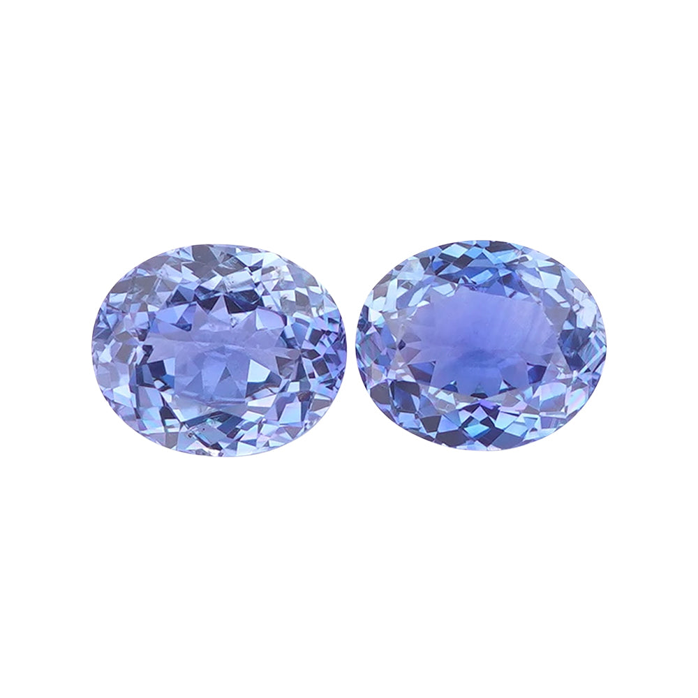 Two violetish-blue oval mixed-cut loose gemstones side by side.