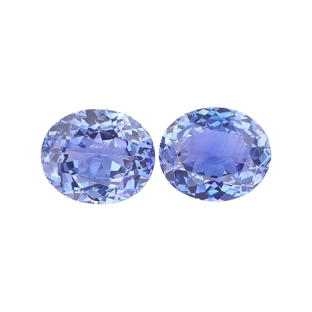 Two violetish-blue oval mixed-cut loose gemstones side by side.