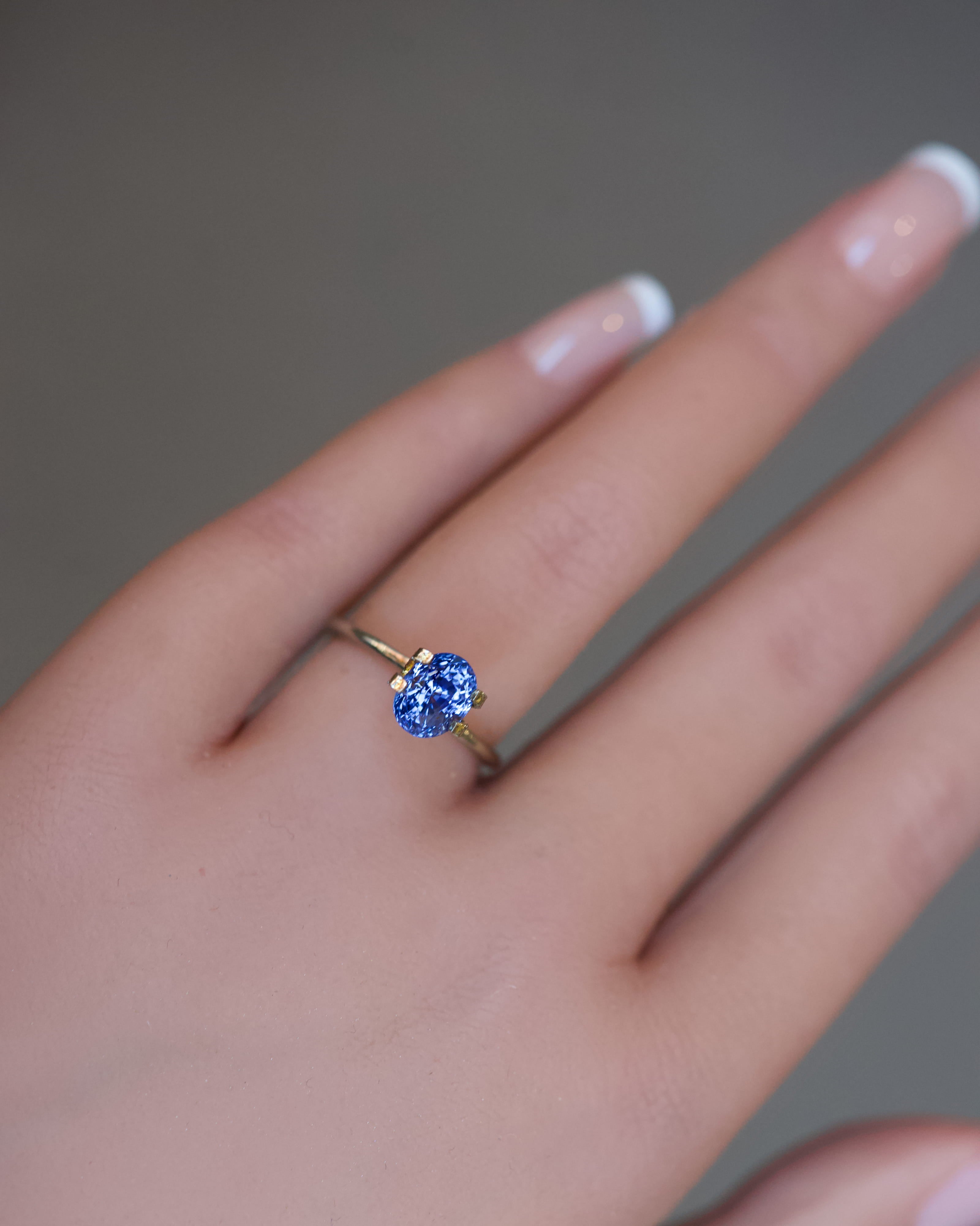 Close view of a shifting blue-violet Ceylon sapphire in an oval cut, worn in a temporary setting.