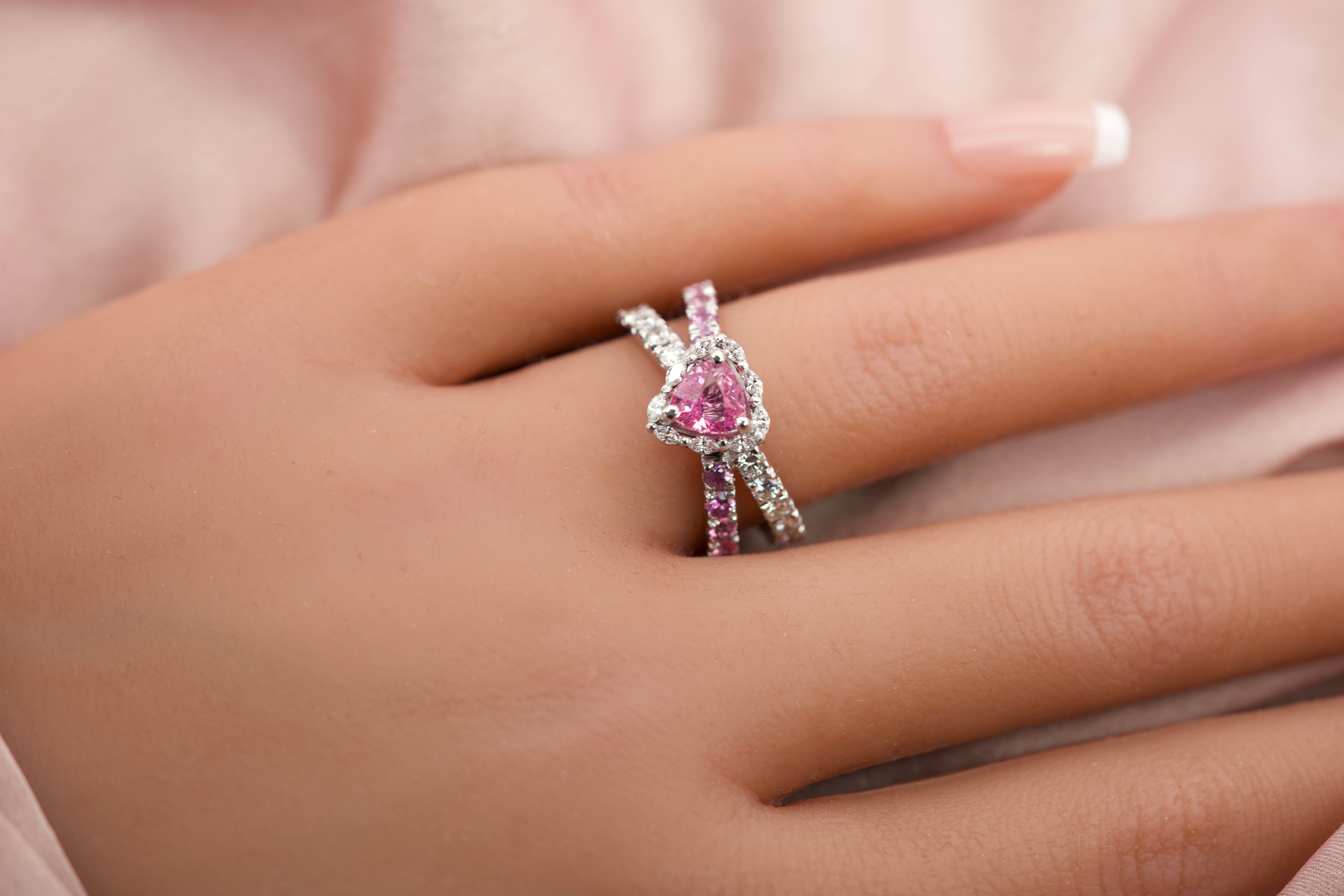 Top-down view of a handcrafted pink sapphire ring on a hand in natural light