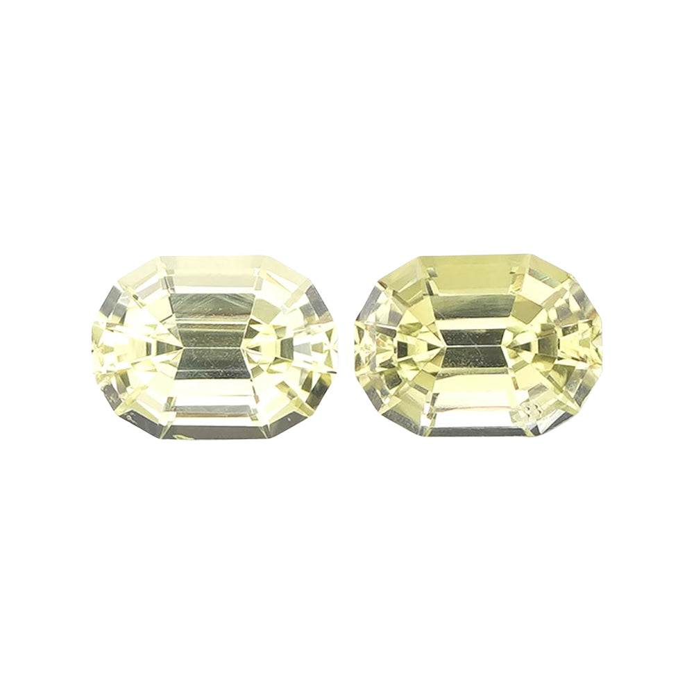 Matched pair of light greenish-yellow rectangular step-cut loose gemstones.