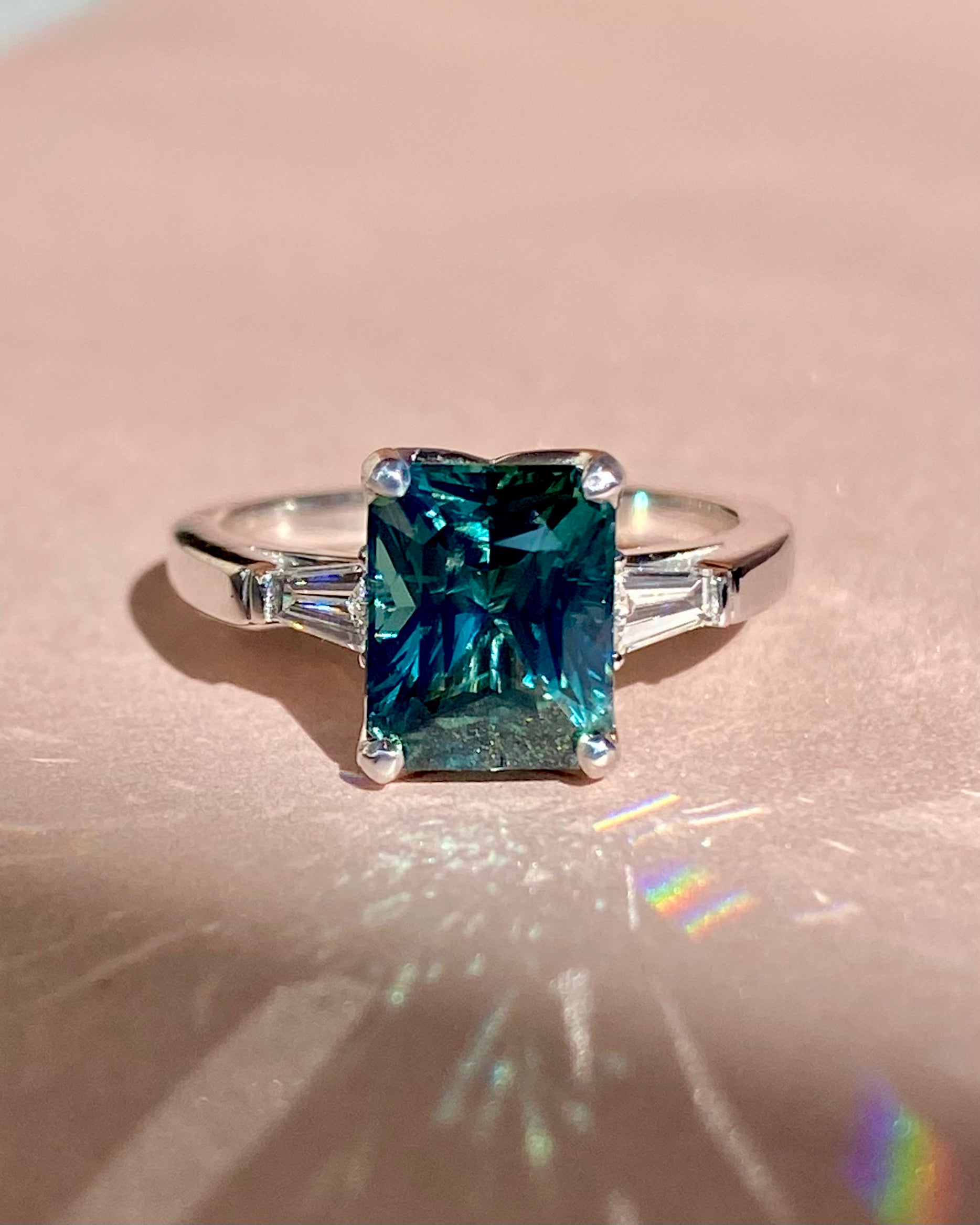 Teal sapphire engagement ring with diamond sides in light