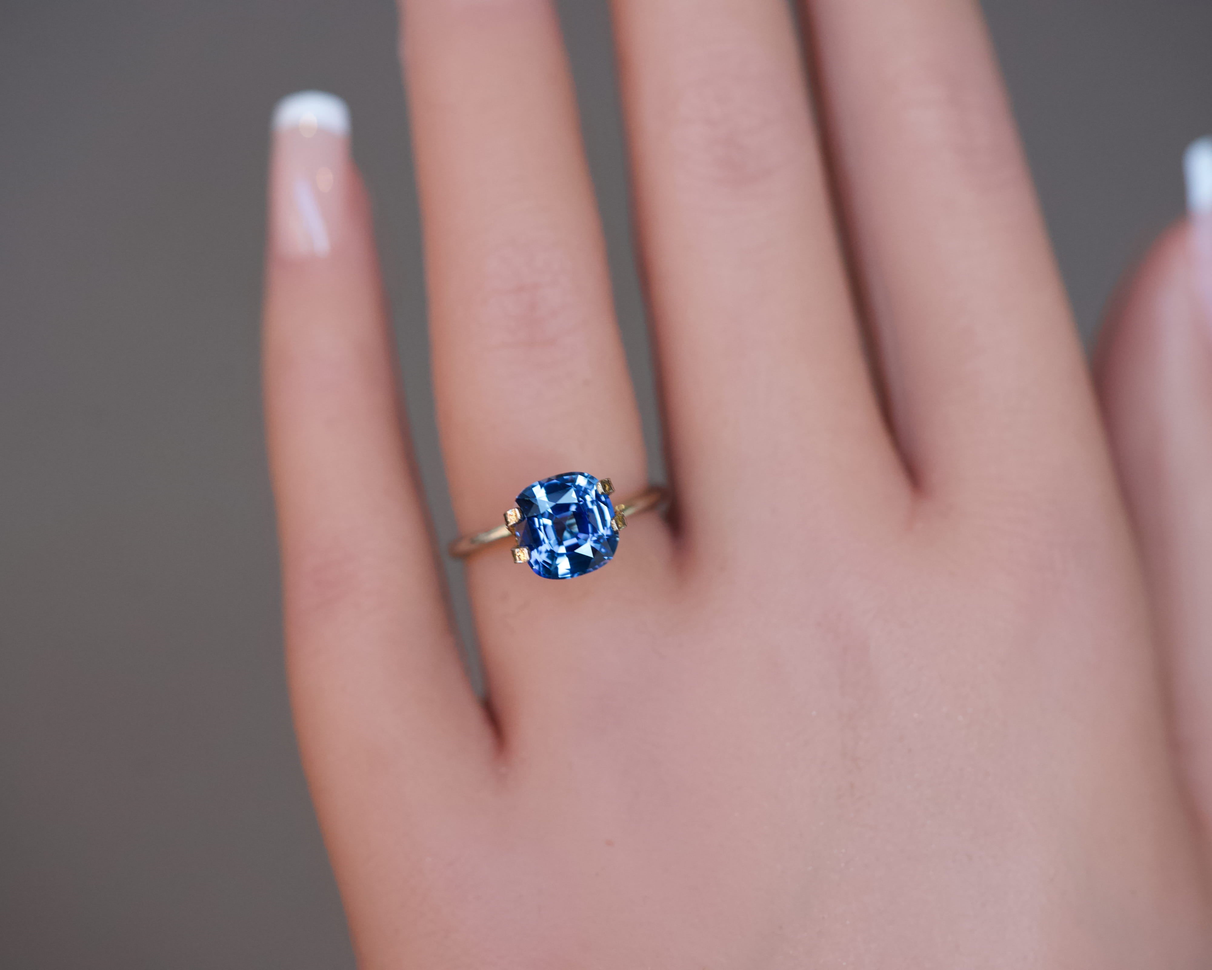 An unheated blue Ceylon cushion sapphire shown worn in a simple gold ring setting.
