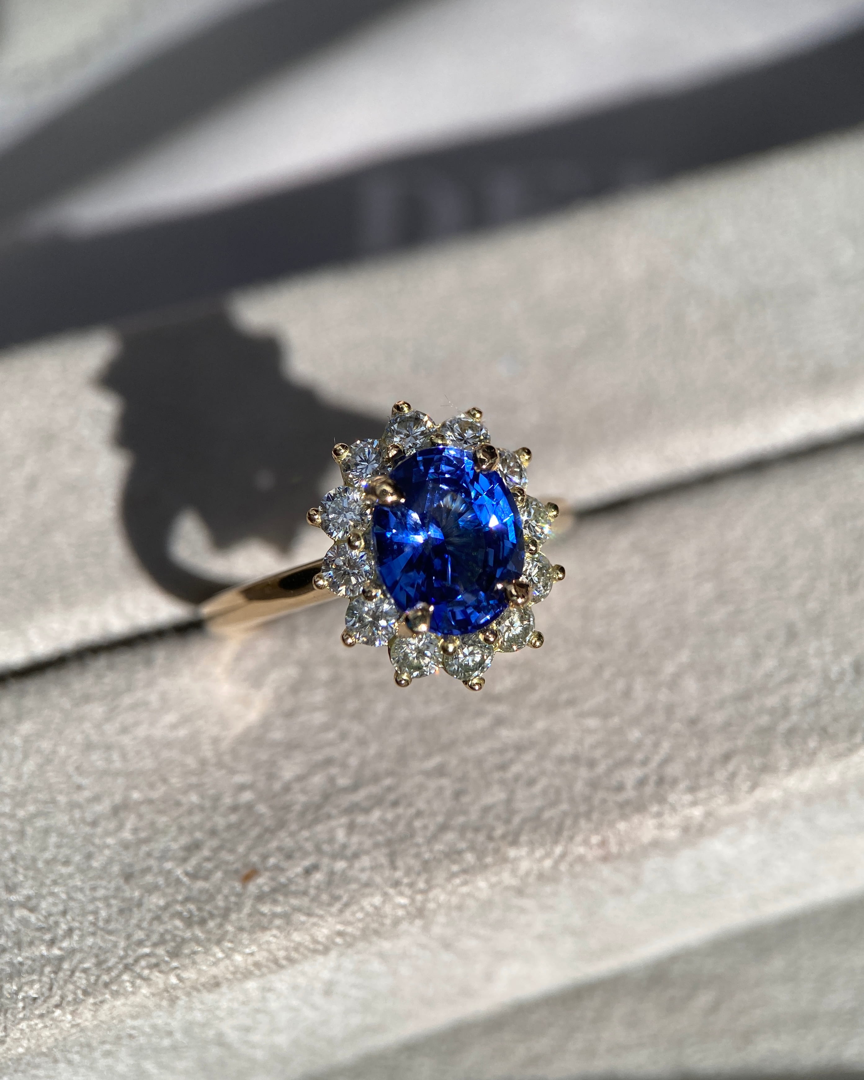 Vivid blue sapphire engagement ring catching direct sunlight to show internal fire and diamond sparkle