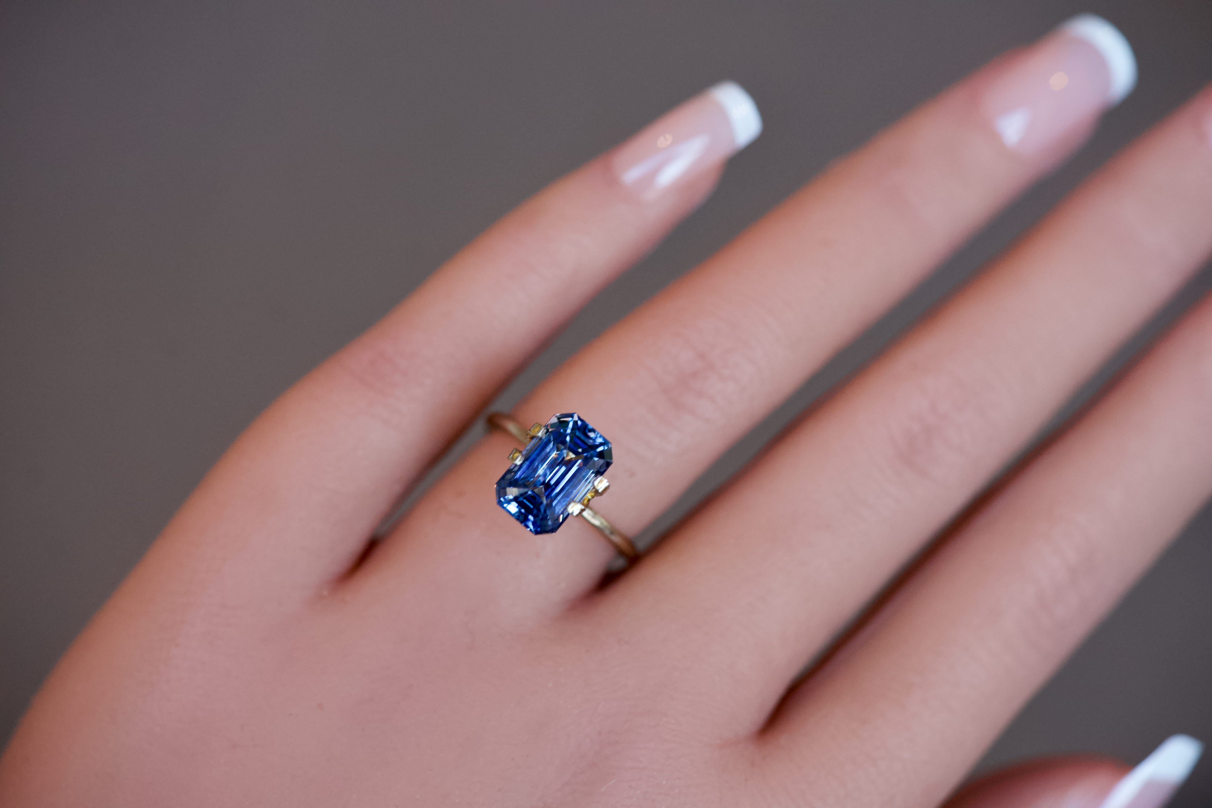 Close-up of a stunning blue Ceylon step-cut sapphire worn in a temporary ring setting.