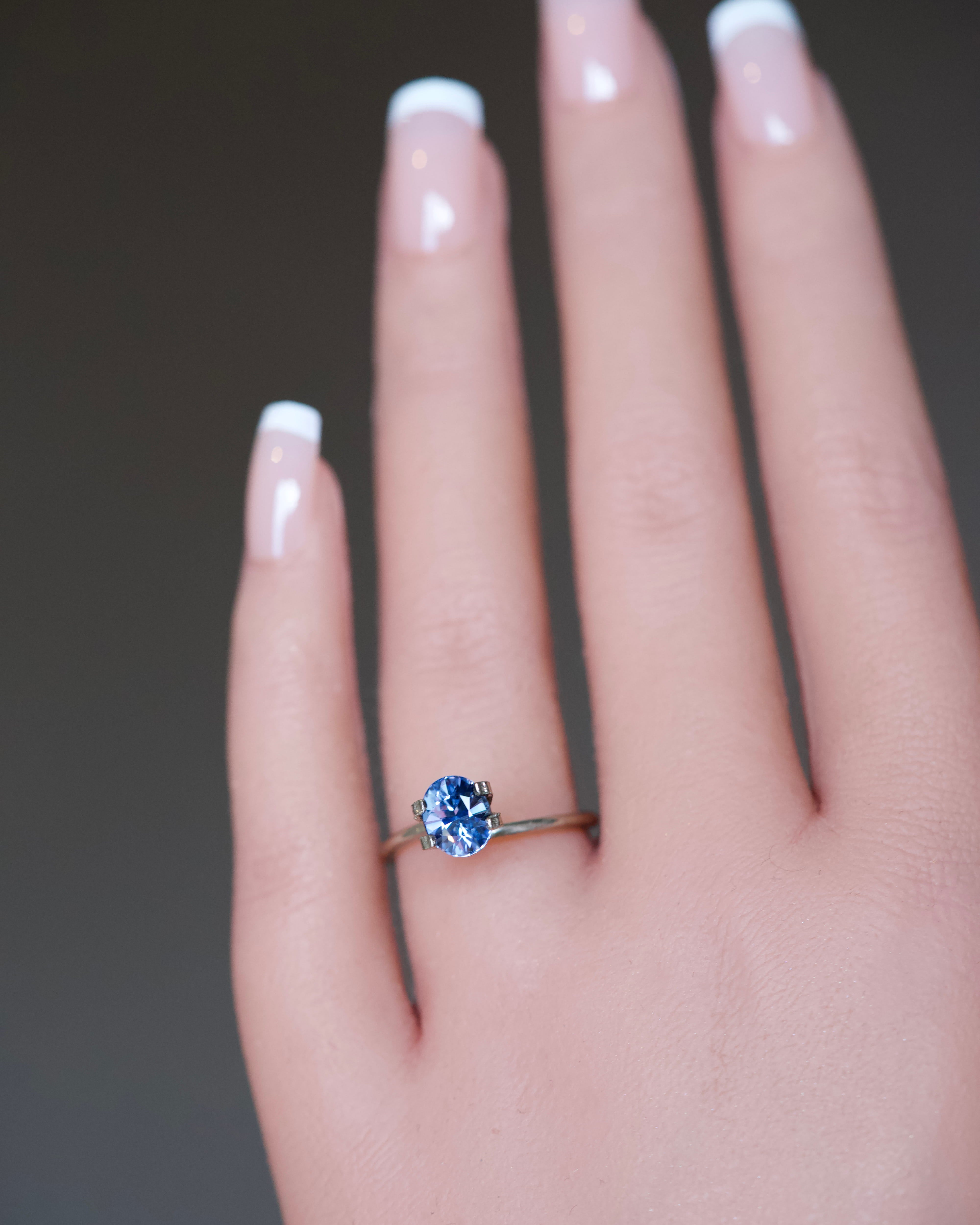 An oval-cut vibrant blue Ceylon sapphire tried on as a ring preview