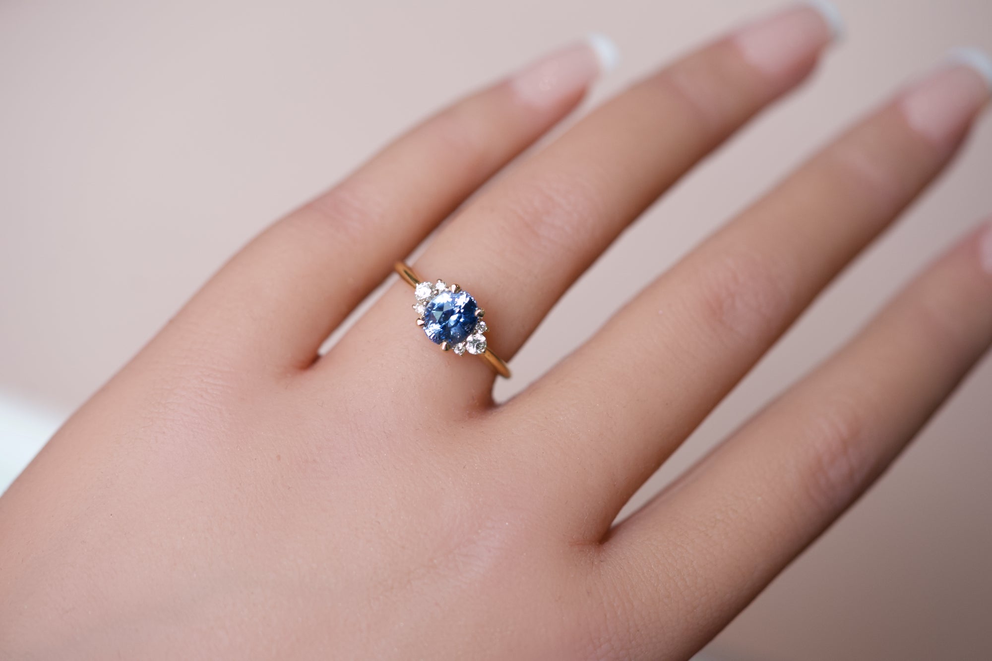 Luxury cornflower blue sapphire and diamond cluster ring worn on a hand