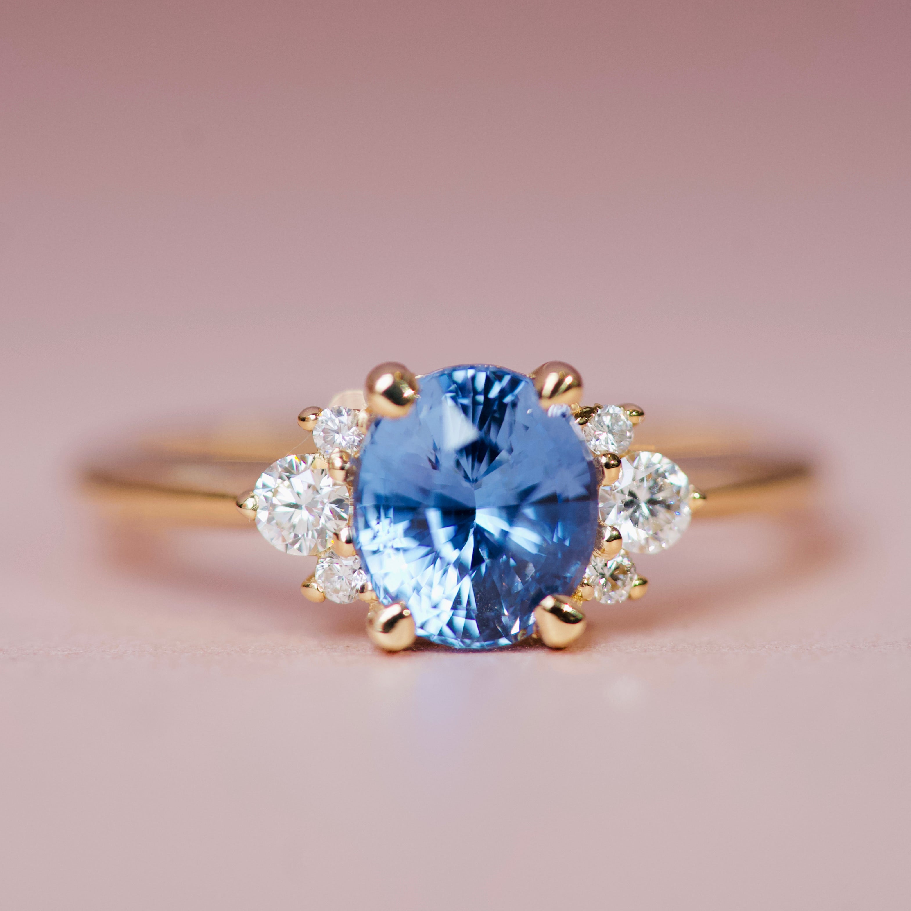 Close-up of an oval cornflower blue sapphire in an 18k yellow gold diamond cluster setting