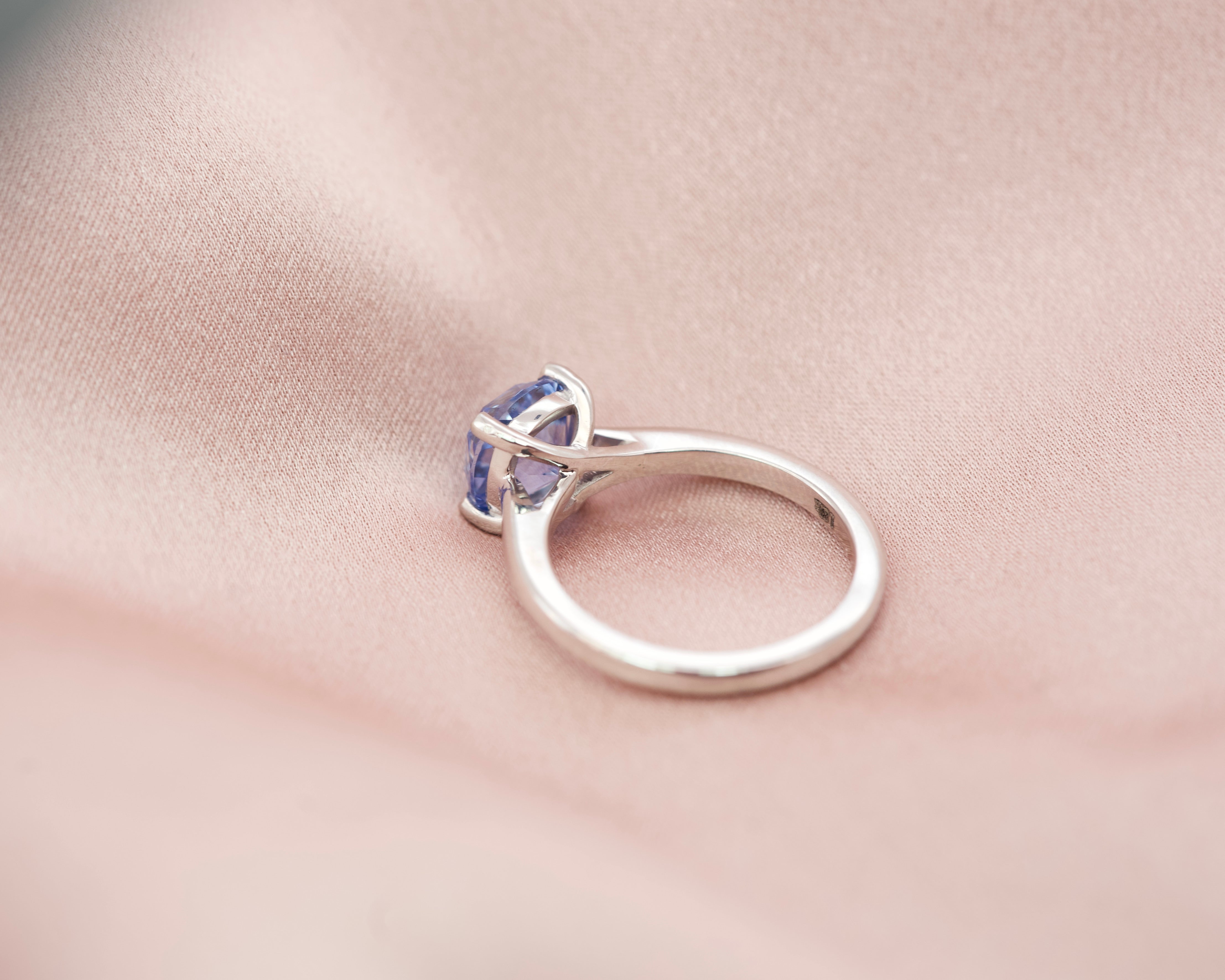 Side profile of a blue sapphire solitaire ring showing the sleek 18k white gold band