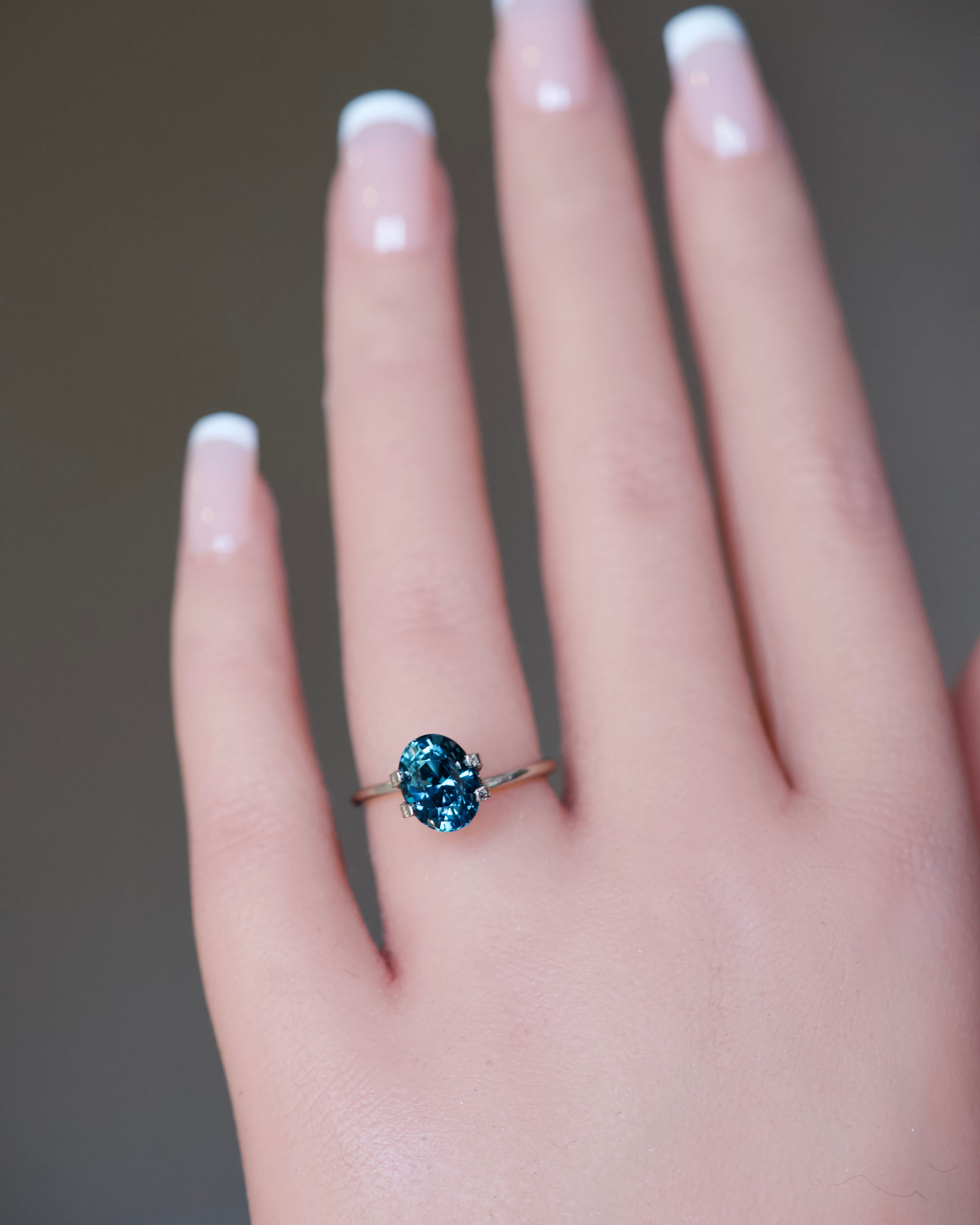 A massive 3.13 carat natural unheated bluish-green oval sapphire presented on a model's ring finger.