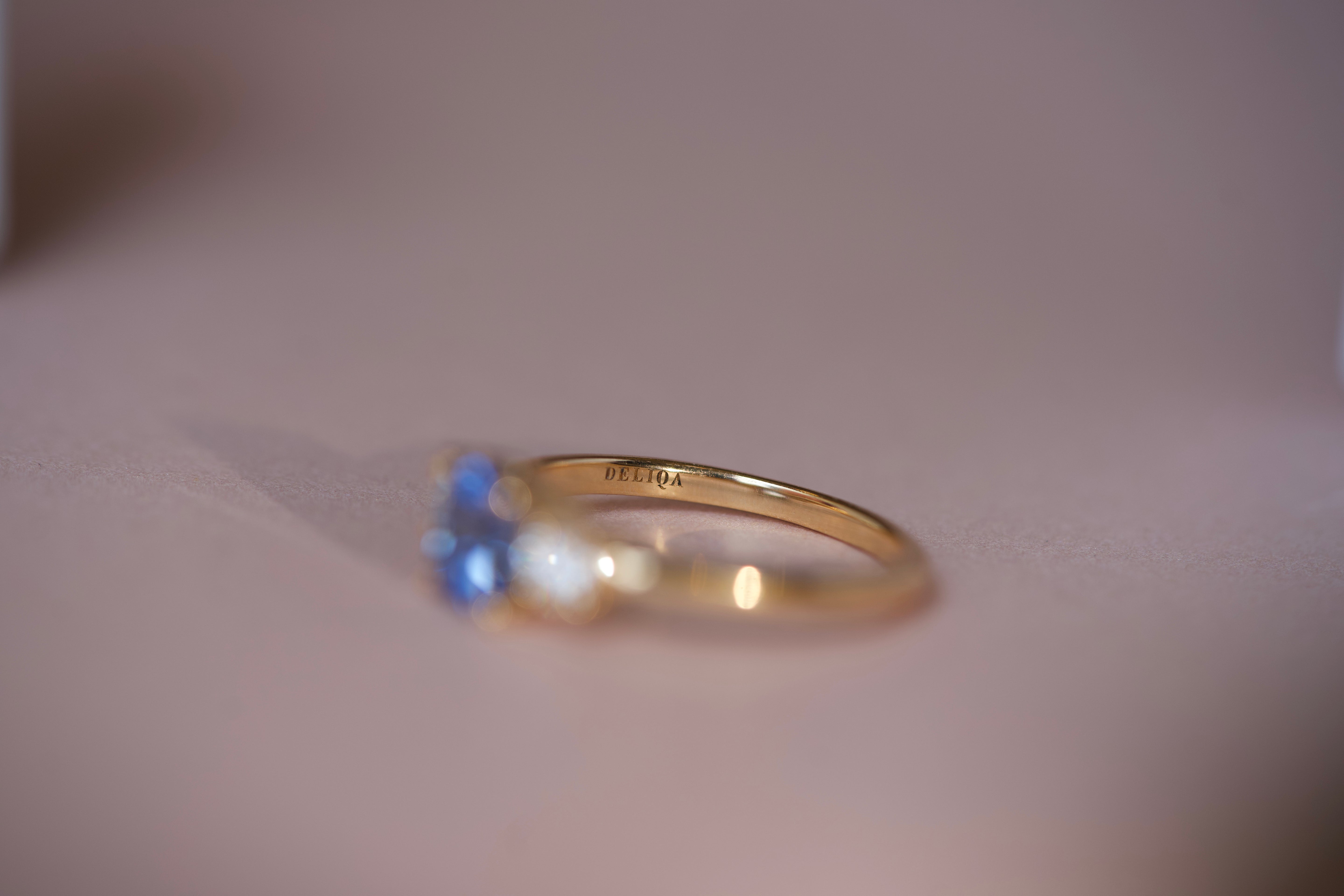 Interior view of custom sapphire ring showing Deliqa brand engraving inside 18k yellow gold band with blue sapphire visible