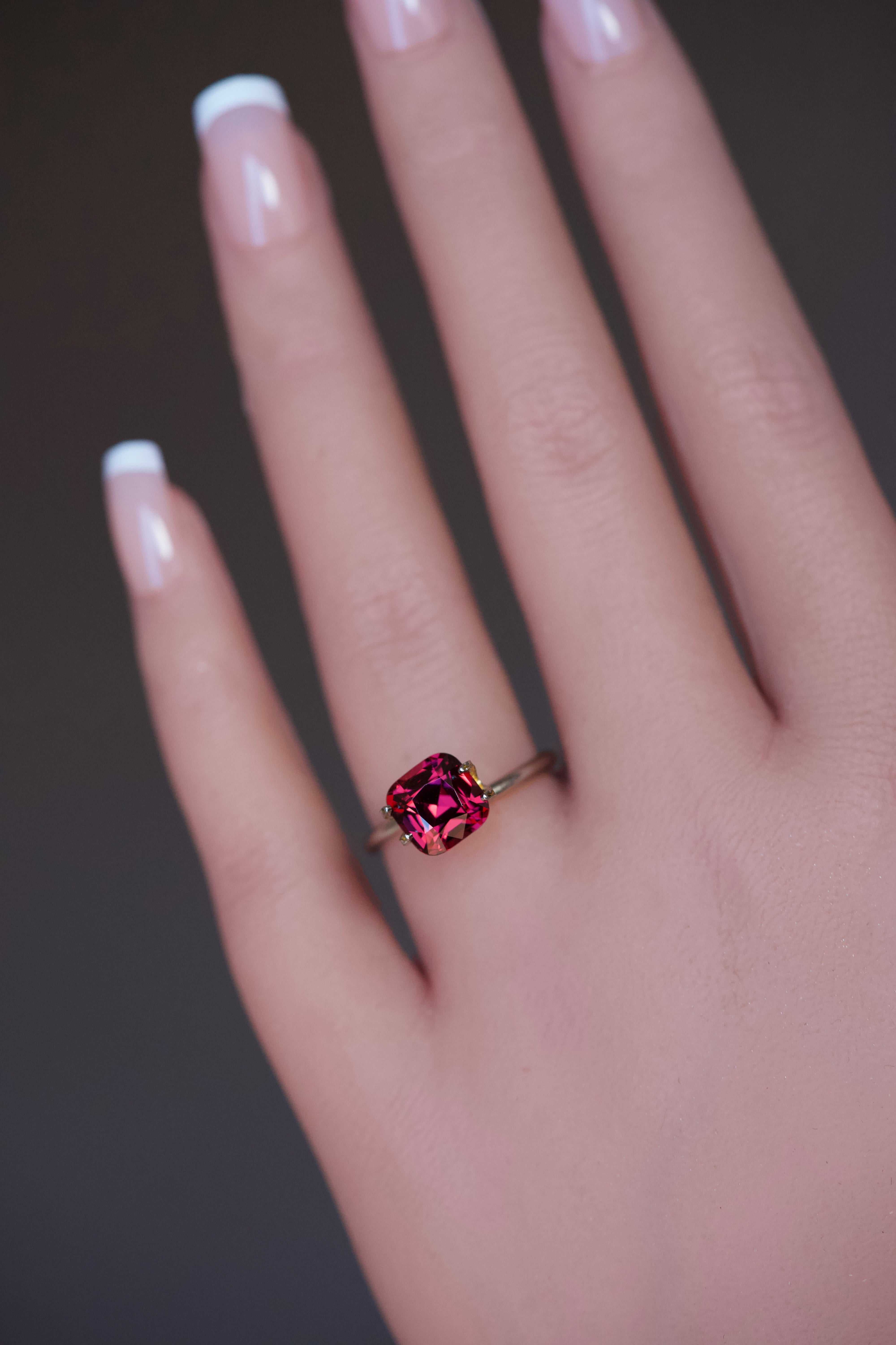 Magenta square cushion garnet stone presented on a hand.