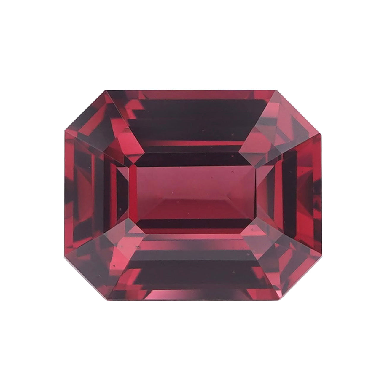 Loose rectangular step-cut orangish pink rhodolite garnet.