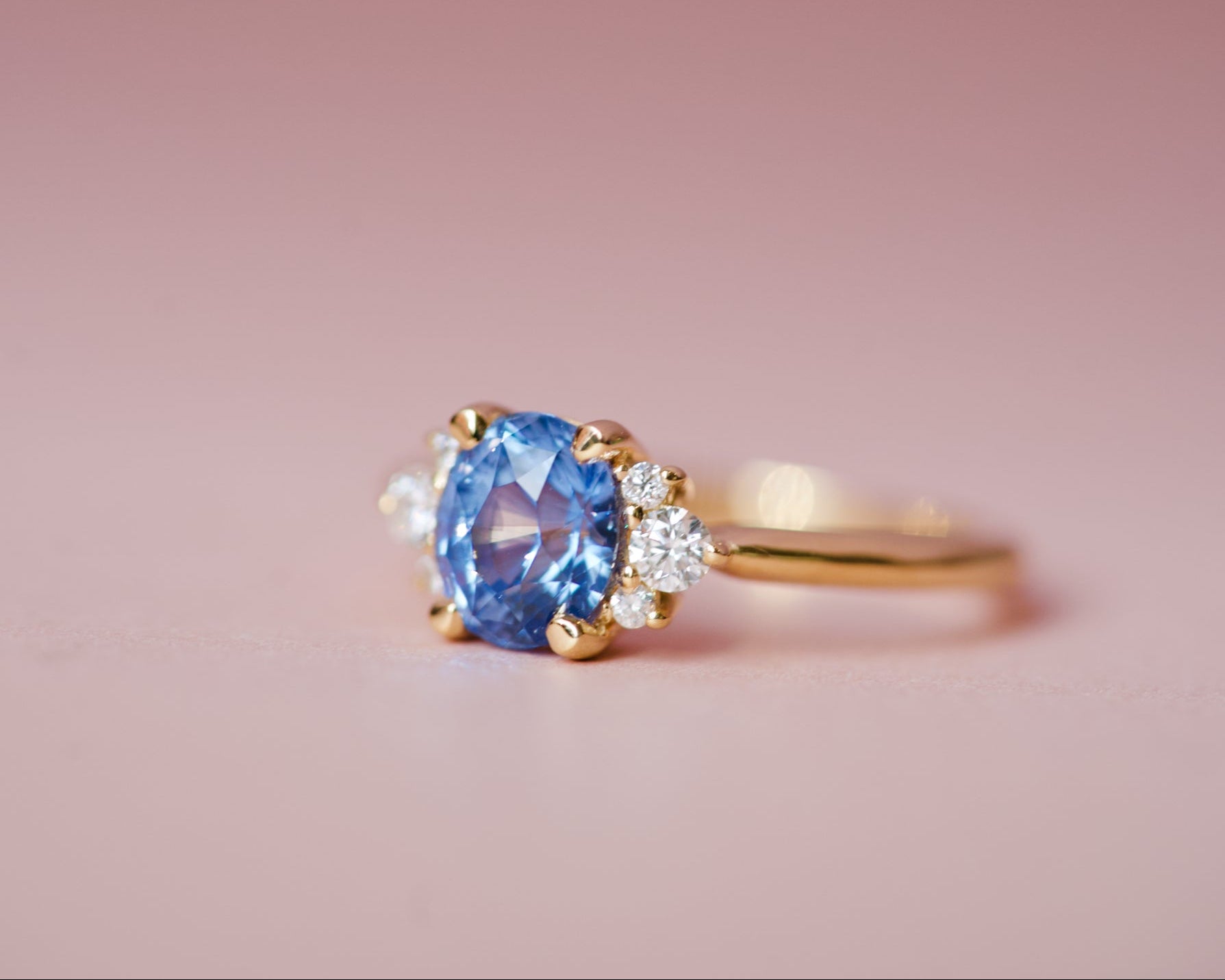 Close-up of an oval cornflower blue sapphire in an 18k yellow gold diamond cluster setting