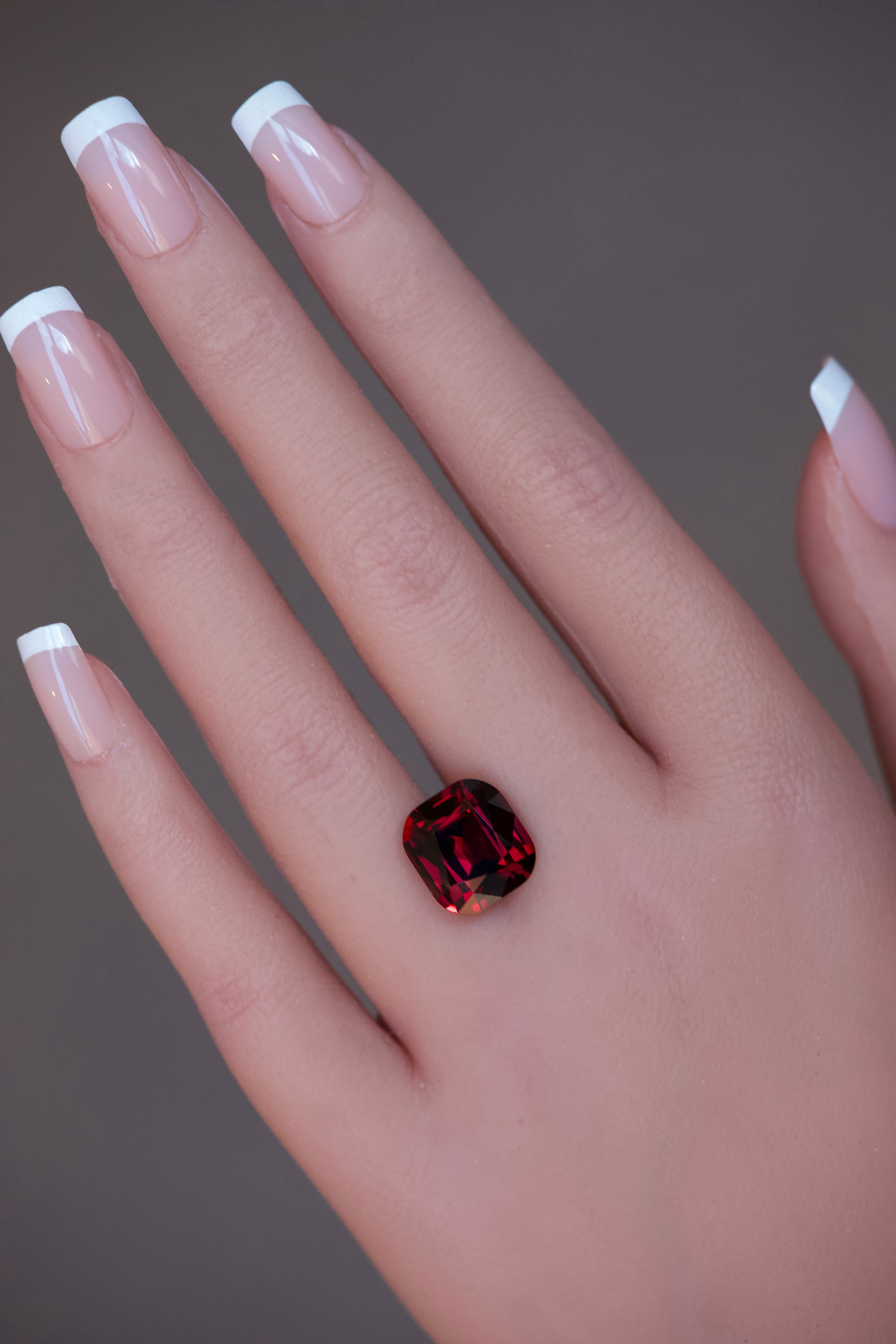 Large purplish-red garnet gem placed over a model's ring finger.