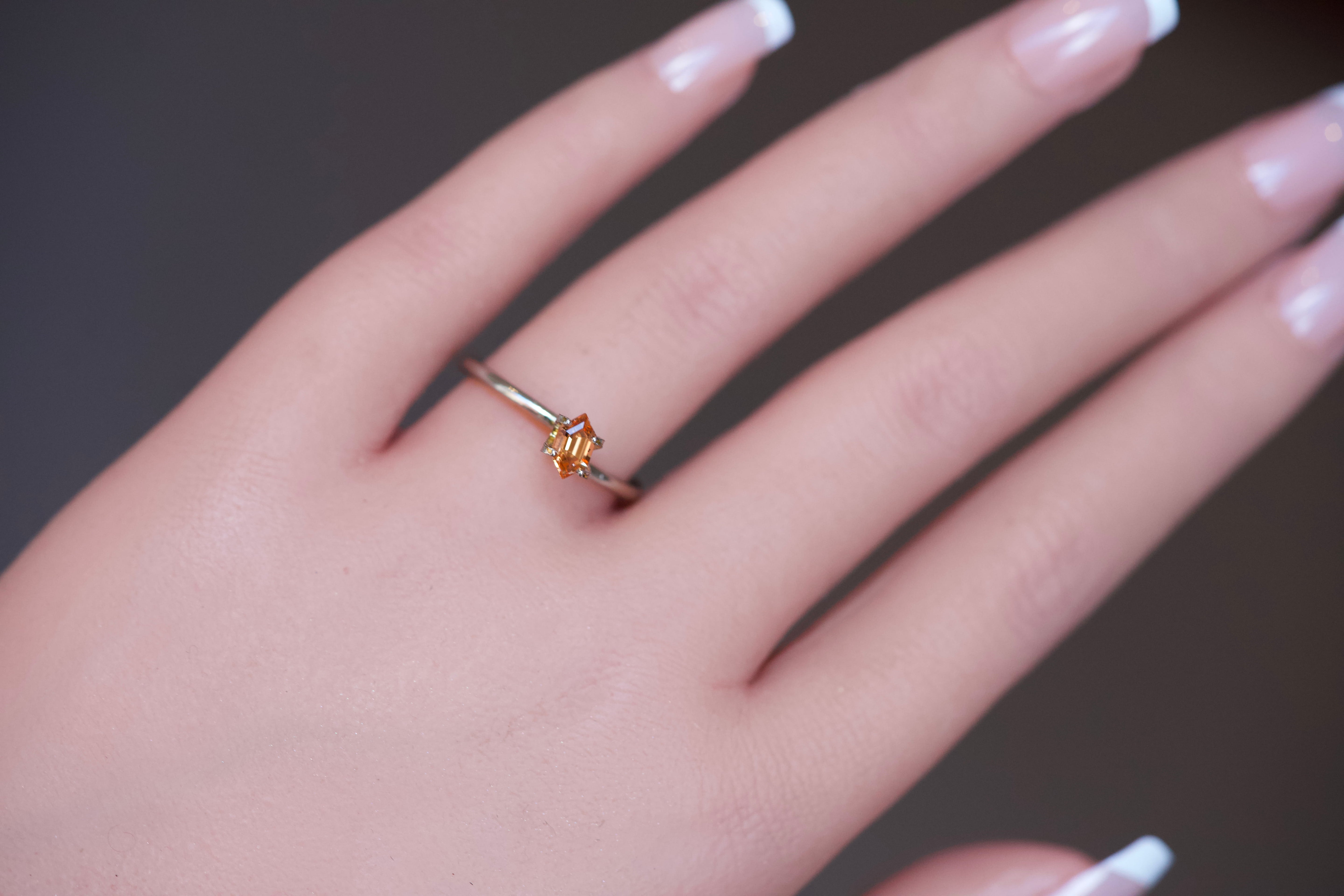 Orange Spessartine Garnet set in a gold ring mockup on a hand.