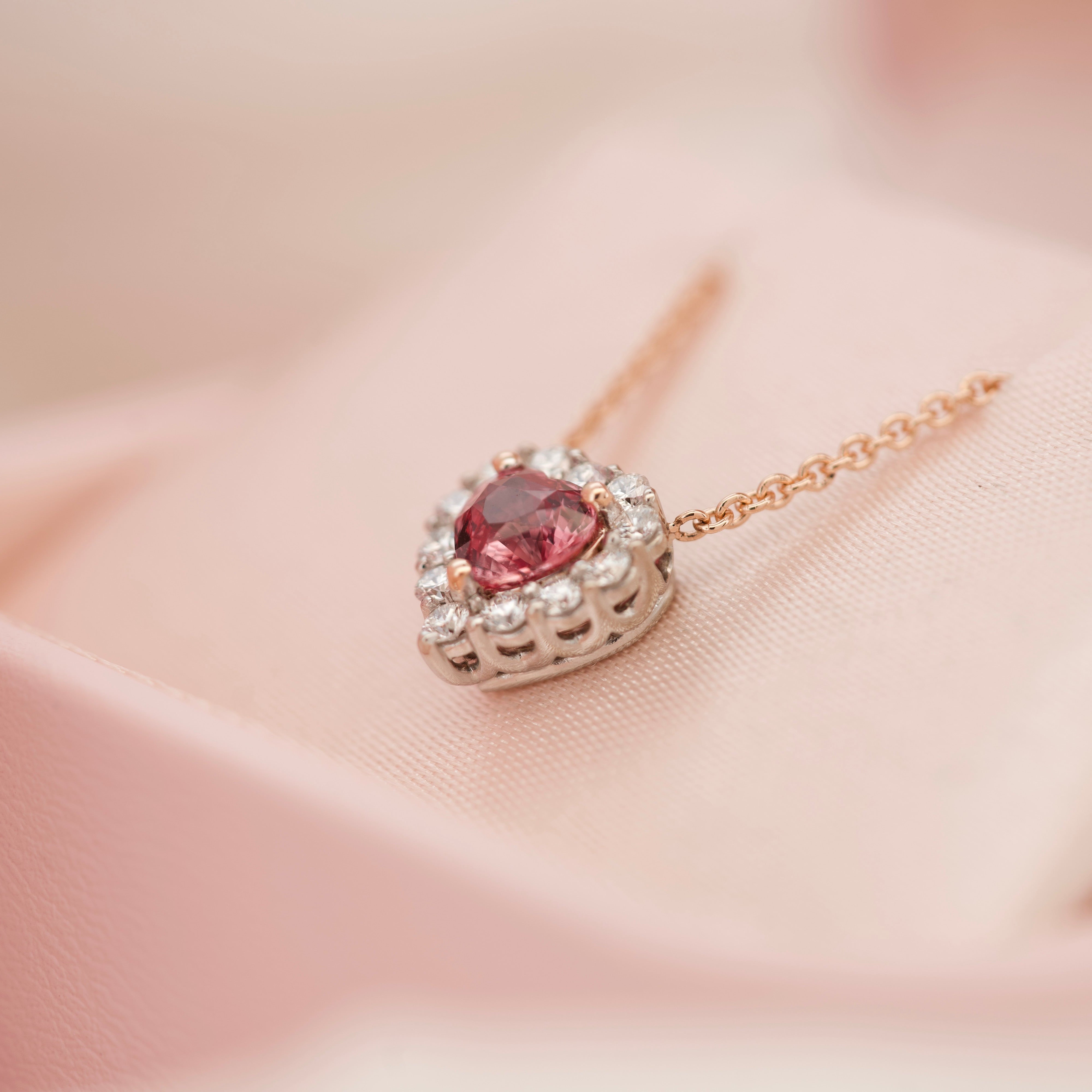 Angled view of a heart sapphire necklace in a pink jewelry box.