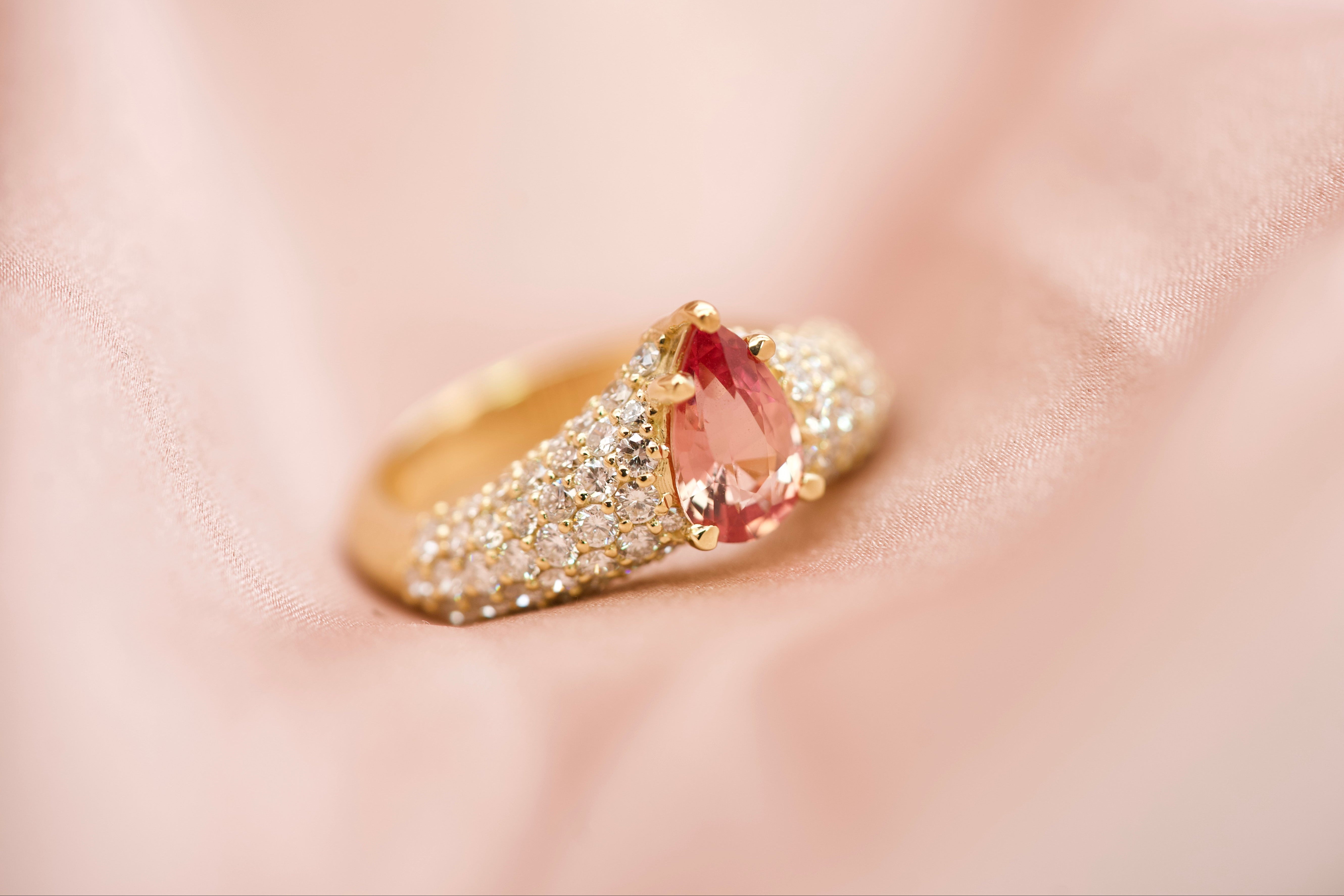 Pear cut padparadscha ring on fabric, lifestyle