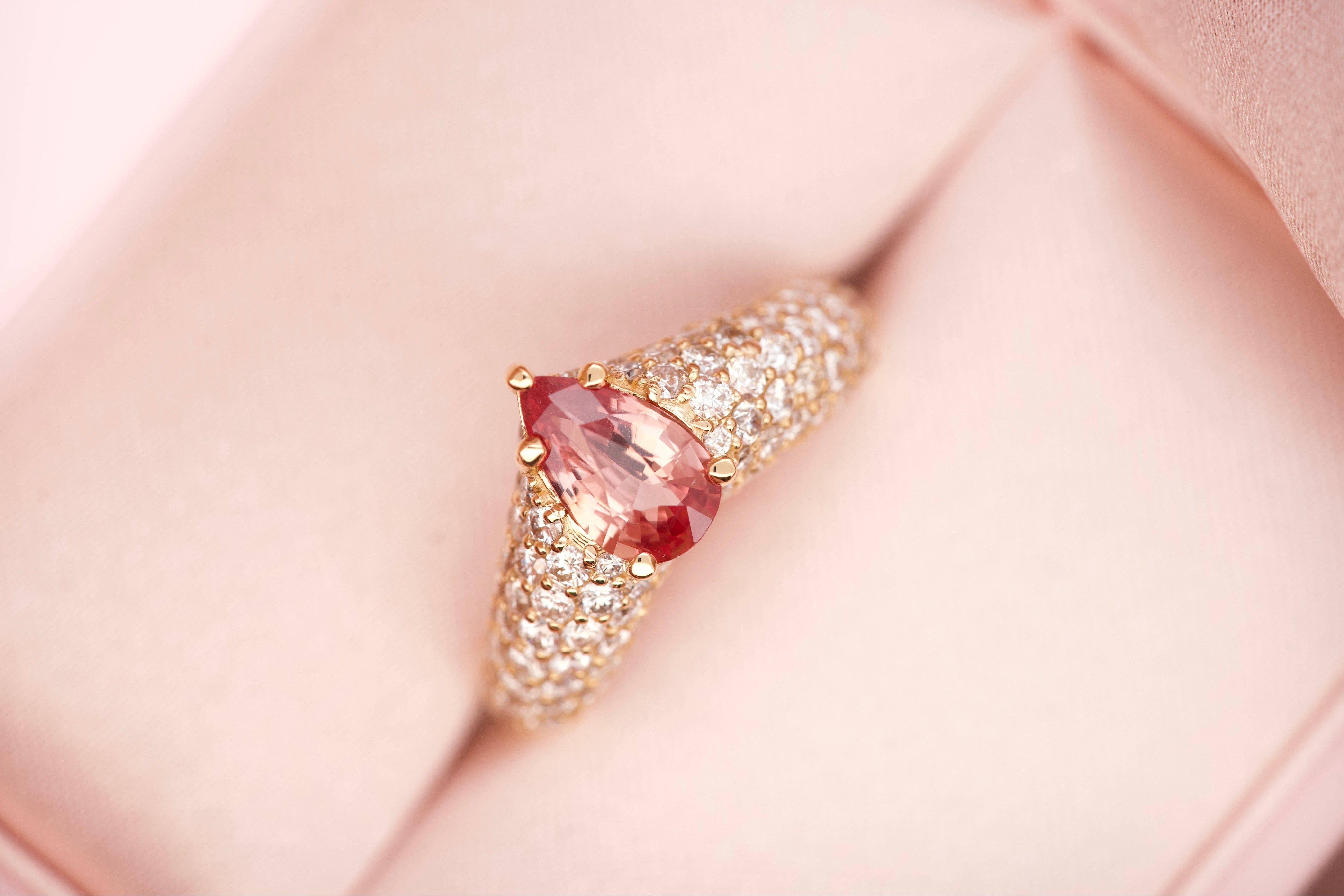 Padparadscha sapphire ring worn on hand, close-up