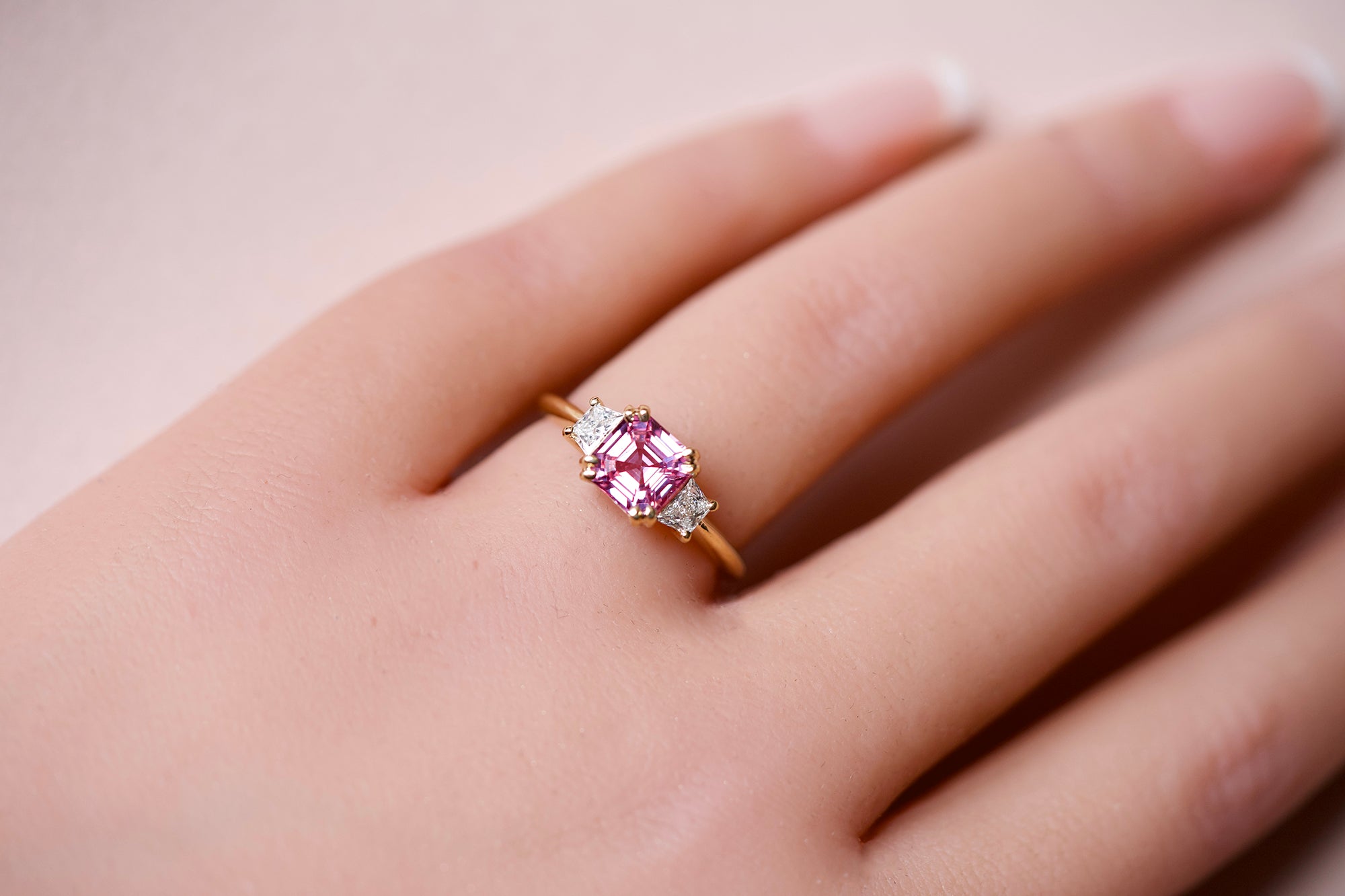 Pink sapphire three stone ring worn on hand