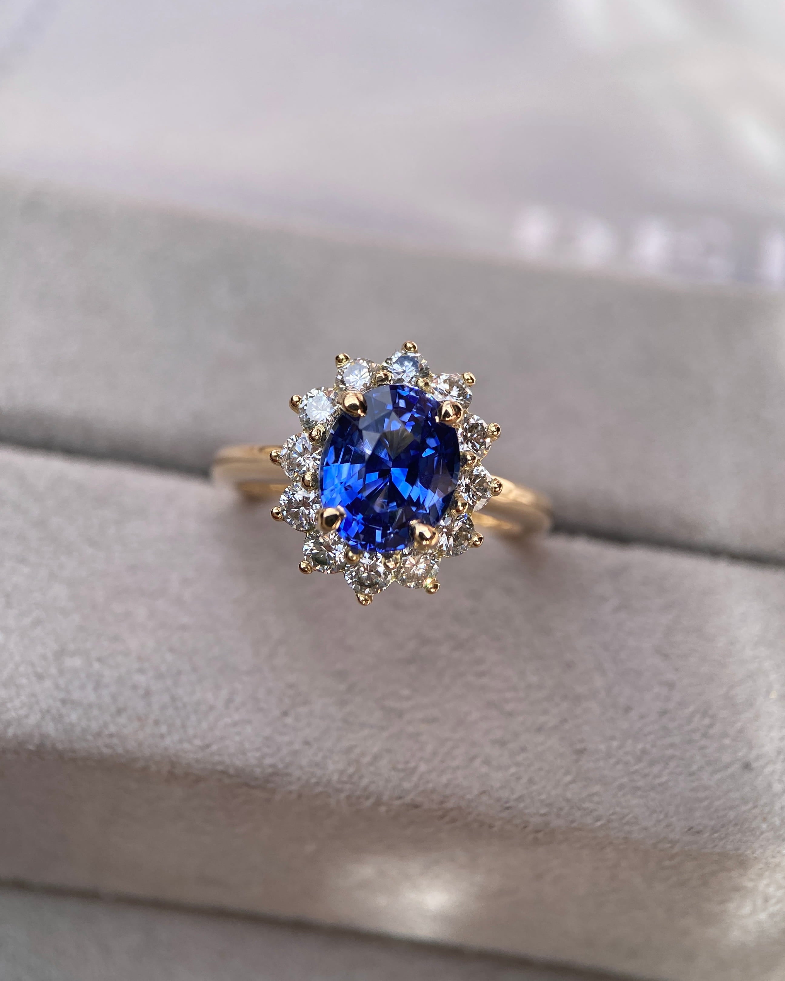 Classic royal style blue sapphire ring with a prominent diamond scalloped halo setting