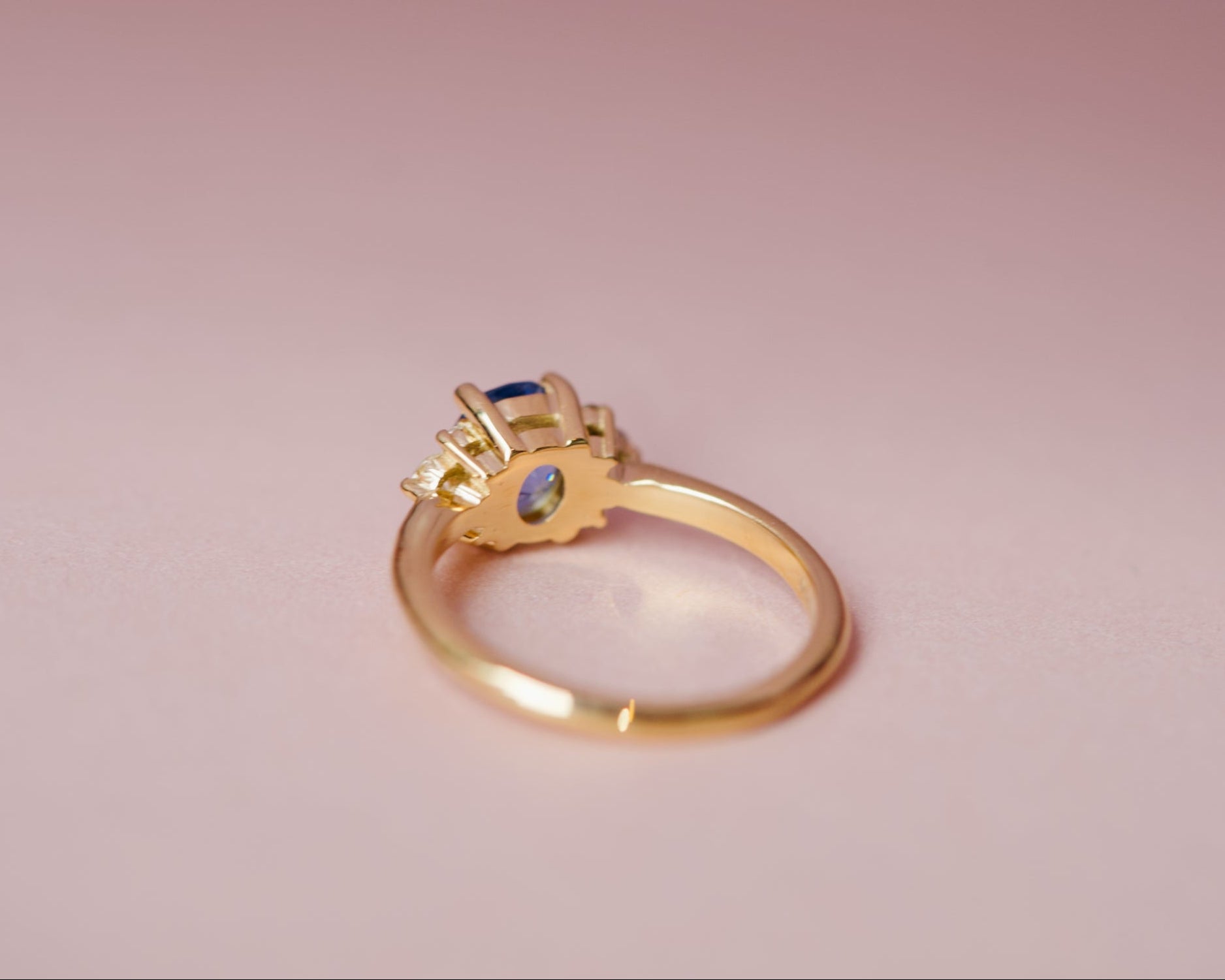 Underside view of the gold basket and setting for an oval sapphire and diamond cluster ring