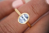 Oval blue sapphire bezel ring worn on hand, close-up