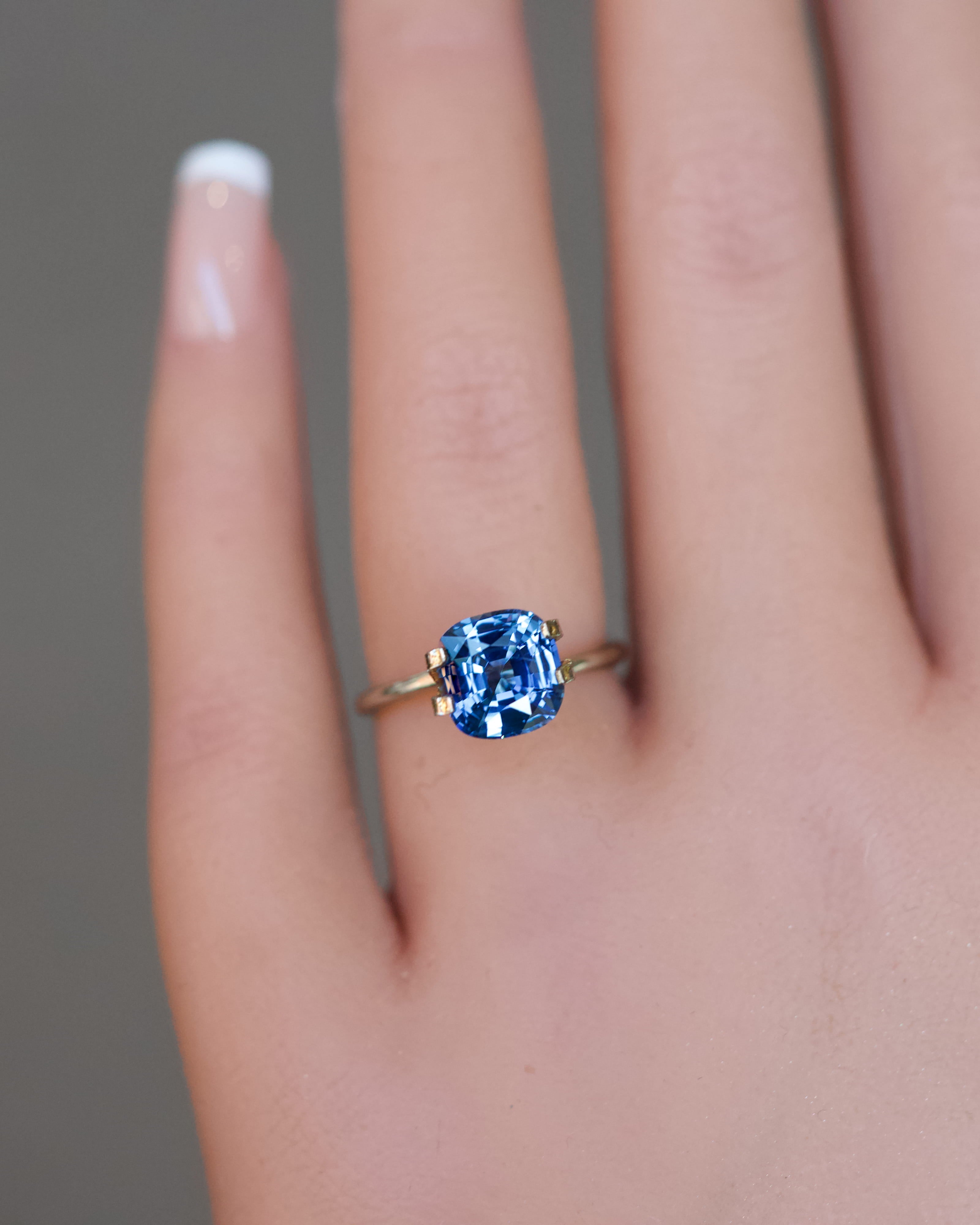 Detailed view of a blue unheated Ceylon cushion sapphire modeled on a hand